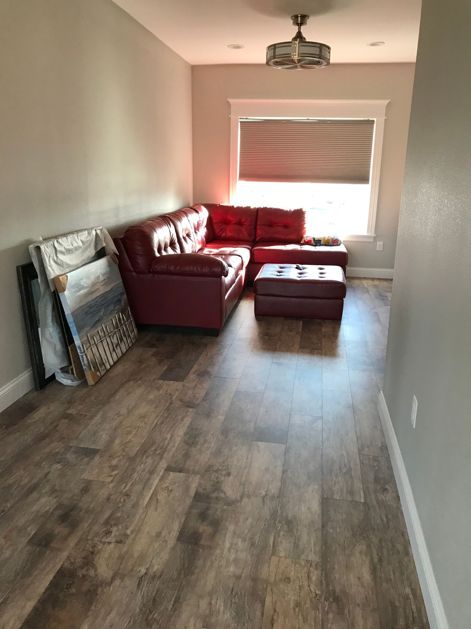 A living room with a red sectional couch and ottoman.
