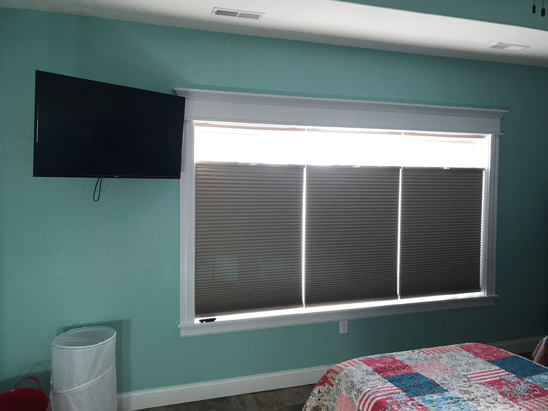 A bedroom with a bed , television , and a large window.
