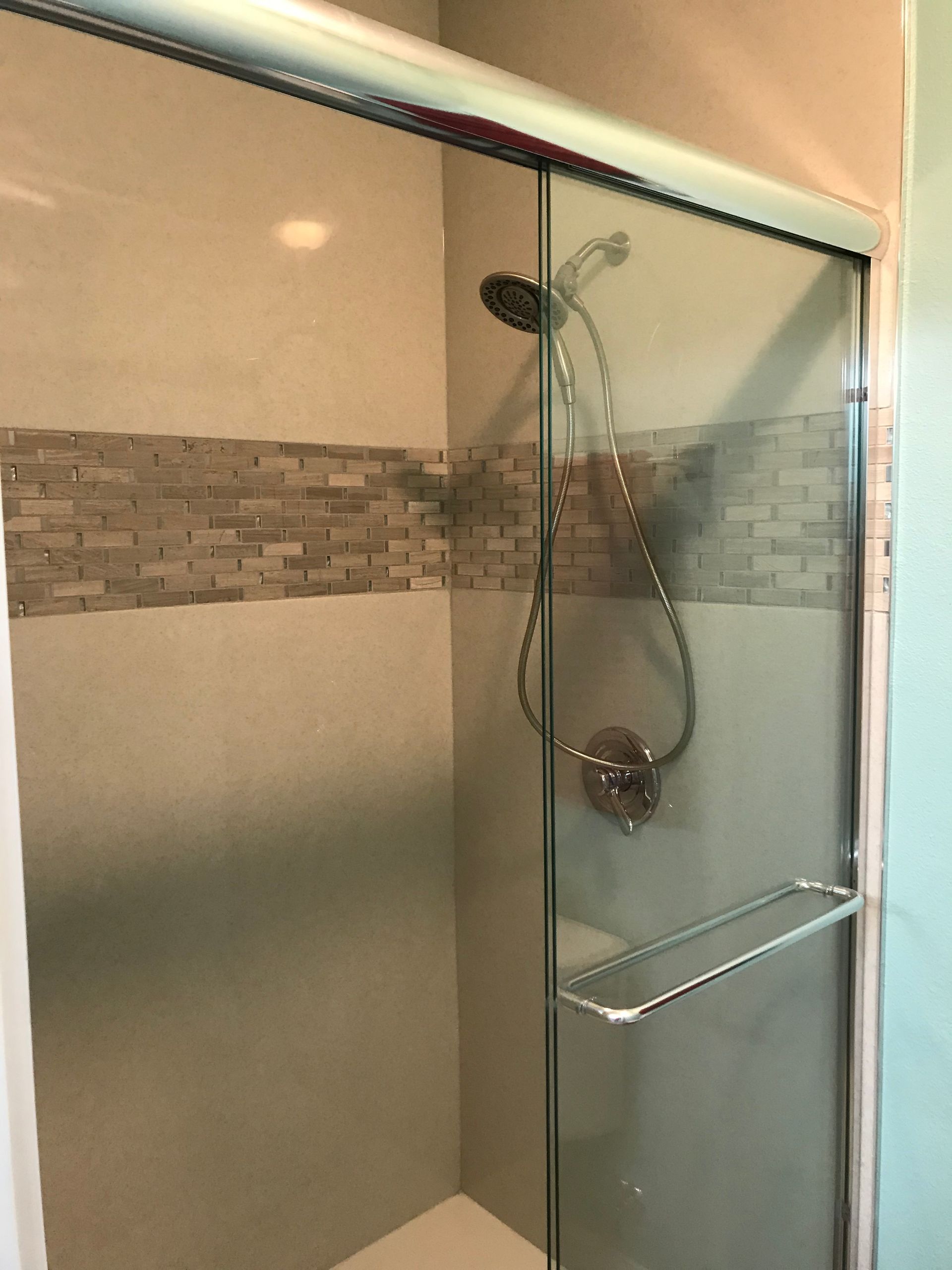A shower with a sliding glass door and a shower head.