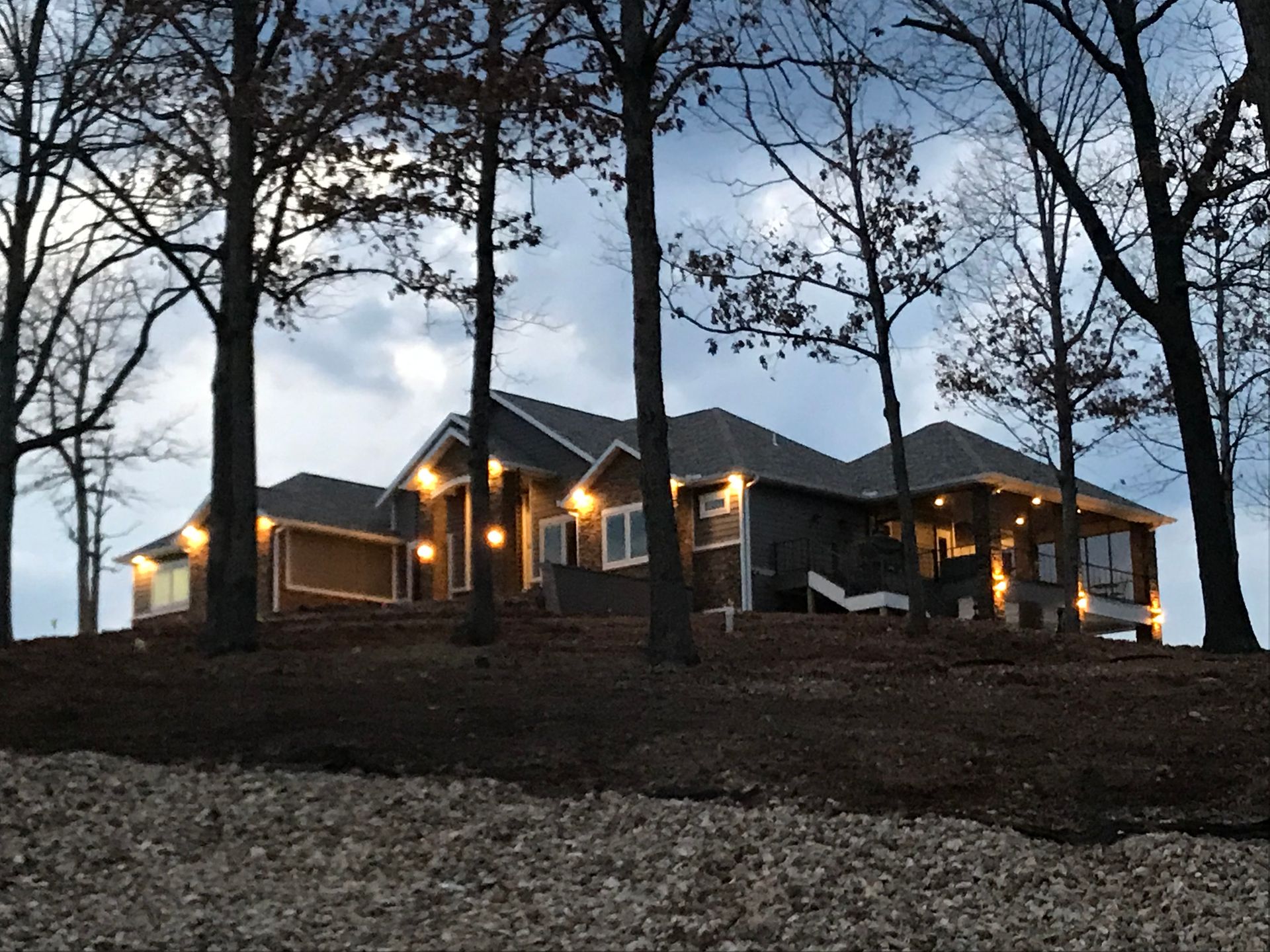 A large house is surrounded by trees and lit up at night.