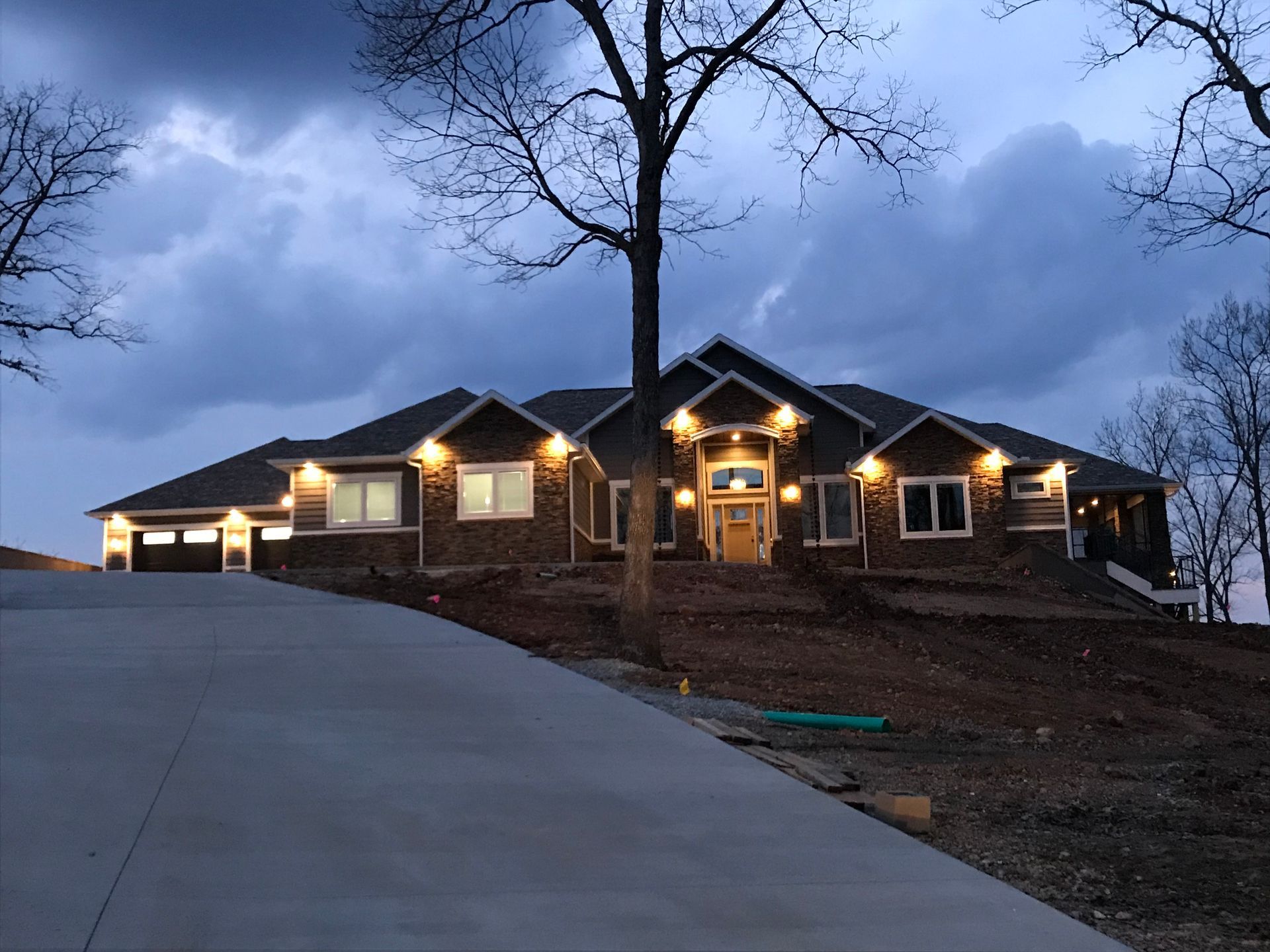 A large house is lit up at night with a tree in front of it.