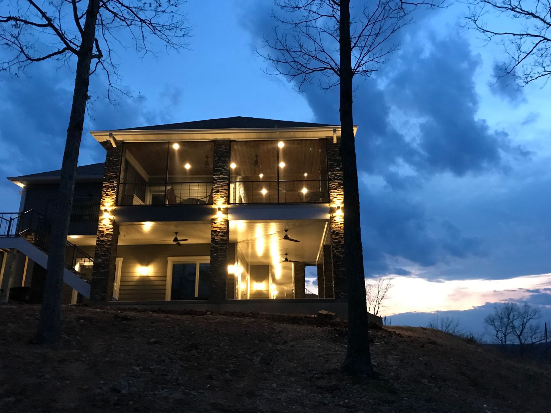 A large house is lit up at night surrounded by trees