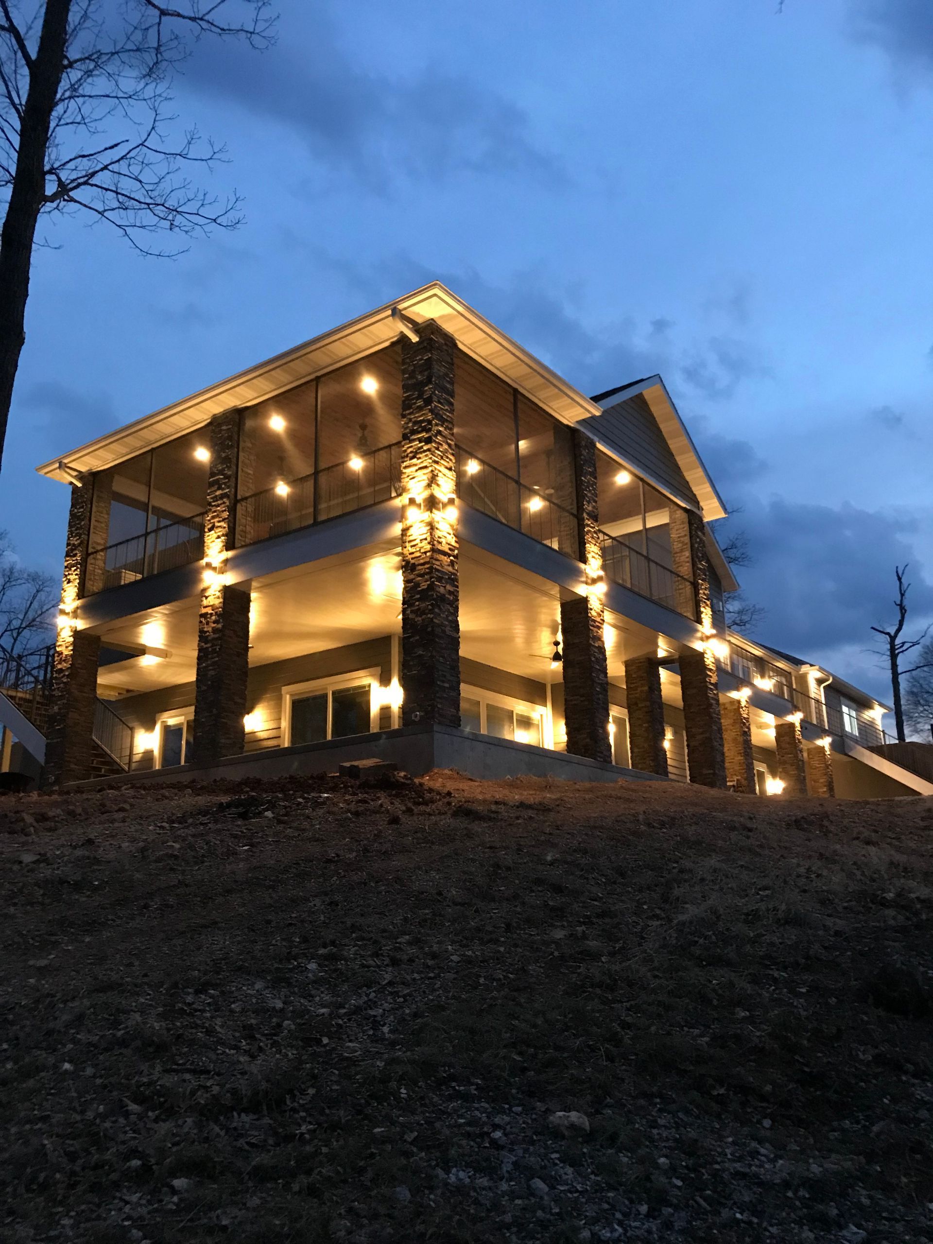 A large house is lit up at night and sitting on top of a hill.