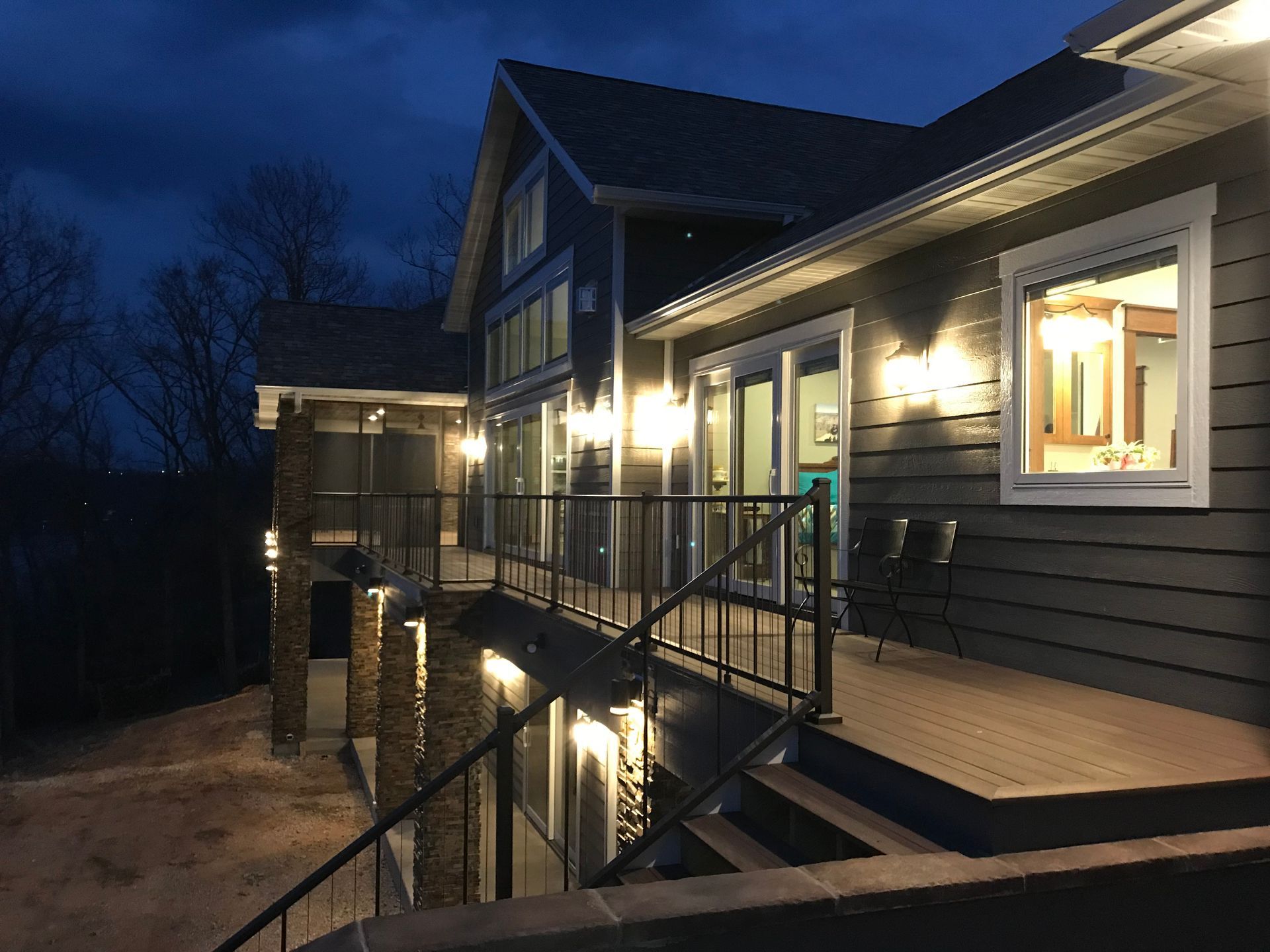 A large house with a large deck is lit up at night.