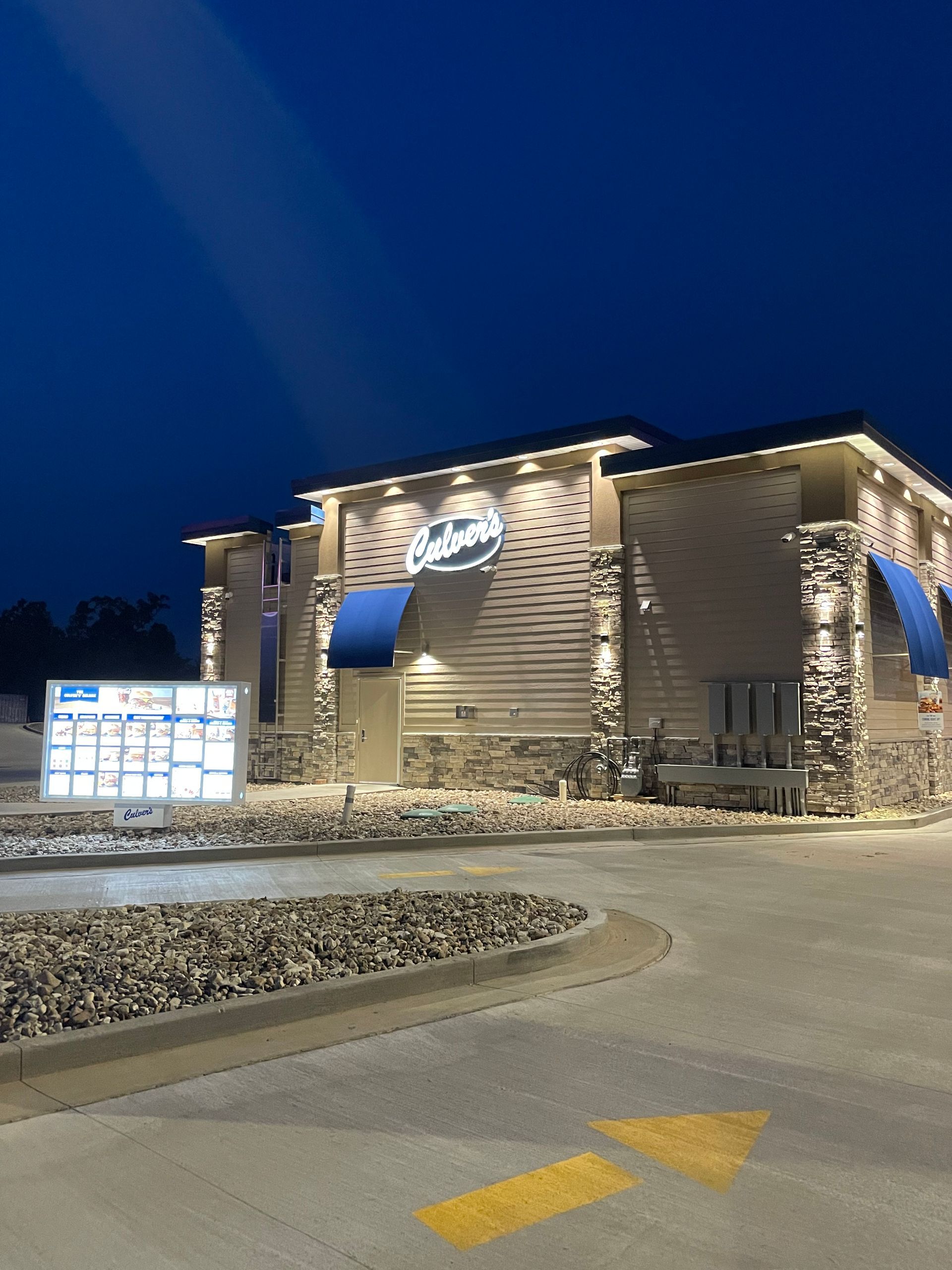 A large building with blue awnings is lit up at night.