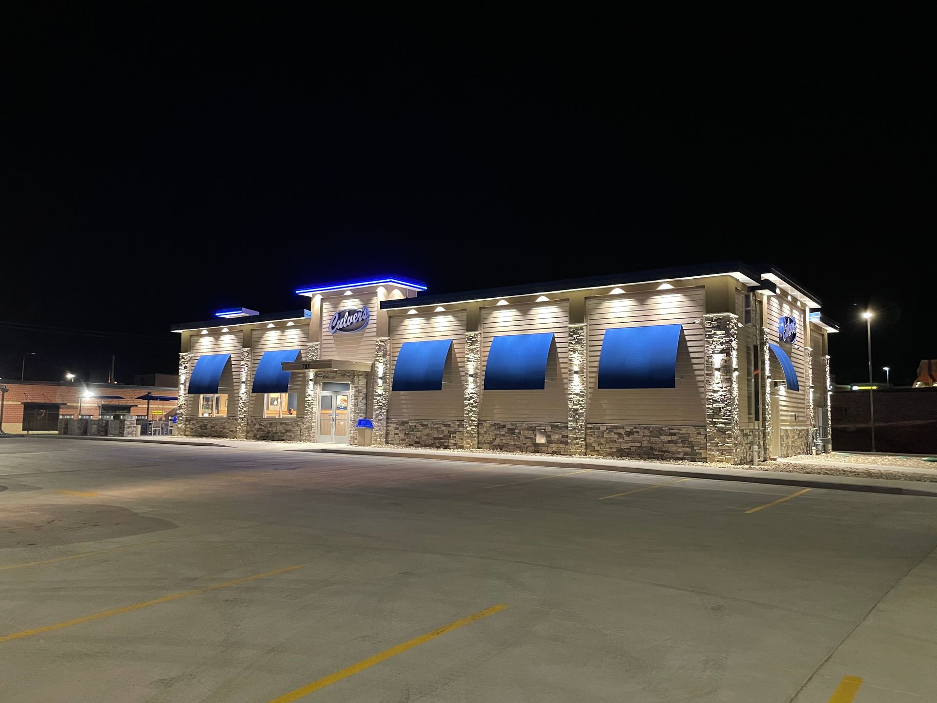 A large building with blue awnings is lit up at night.
