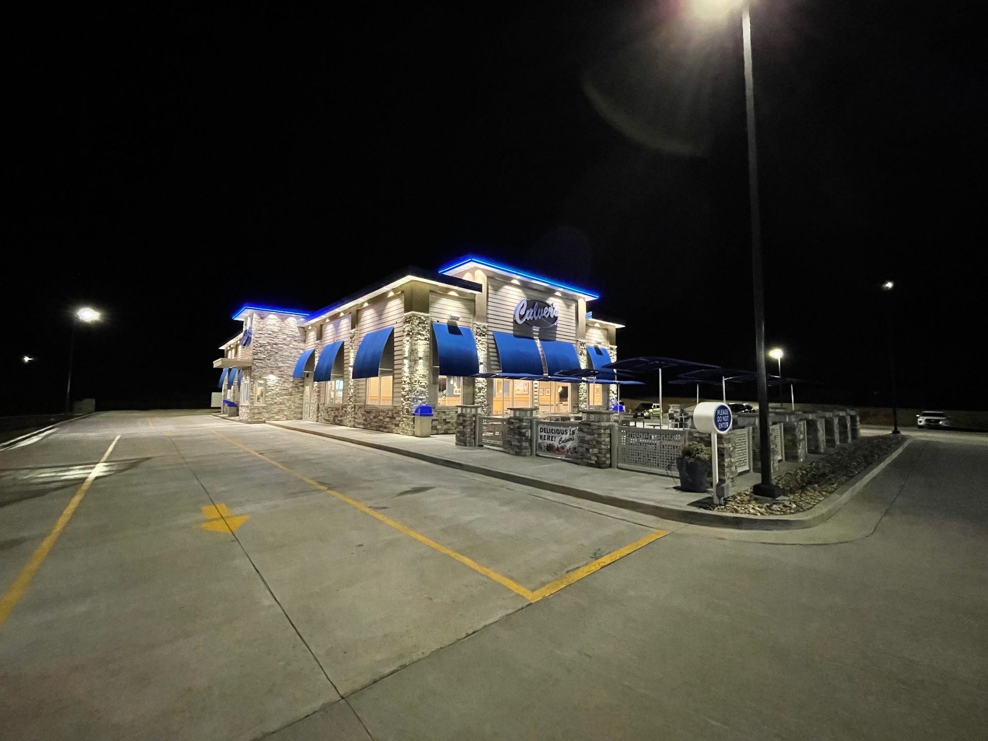 A large building with blue awnings is lit up at night.