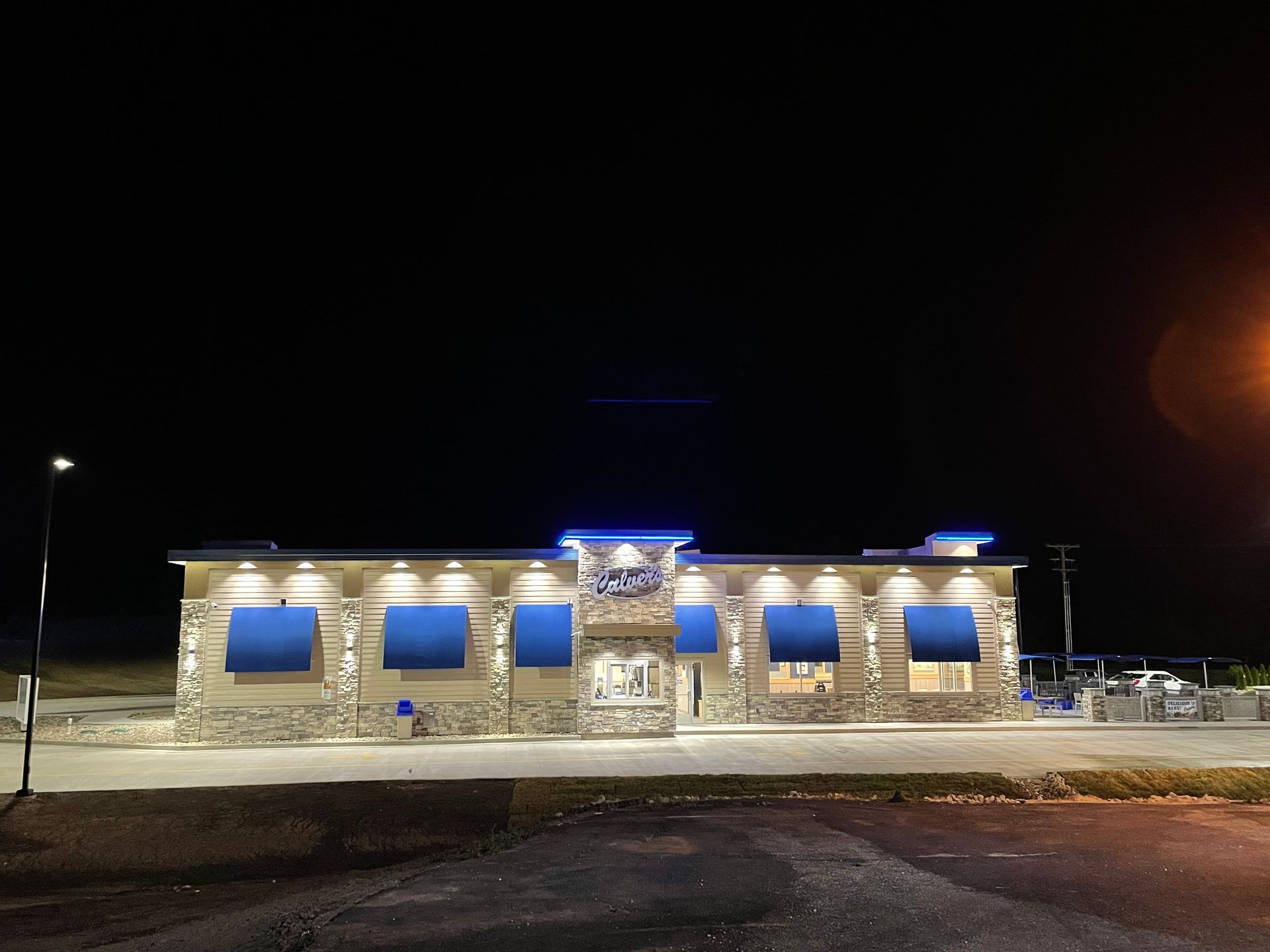 A large building with blue awnings is lit up at night.