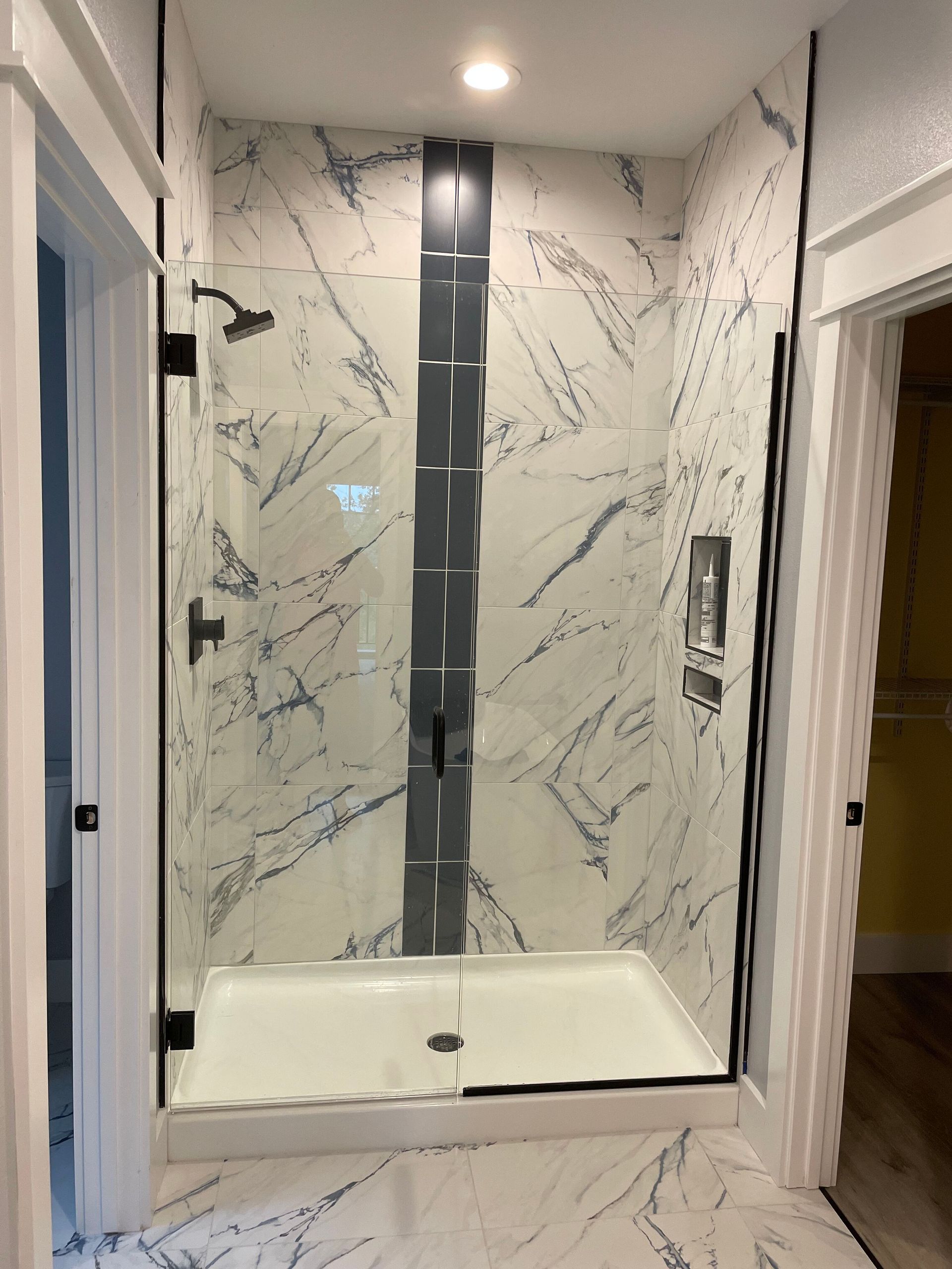 A bathroom with a walk in shower with a marble wall