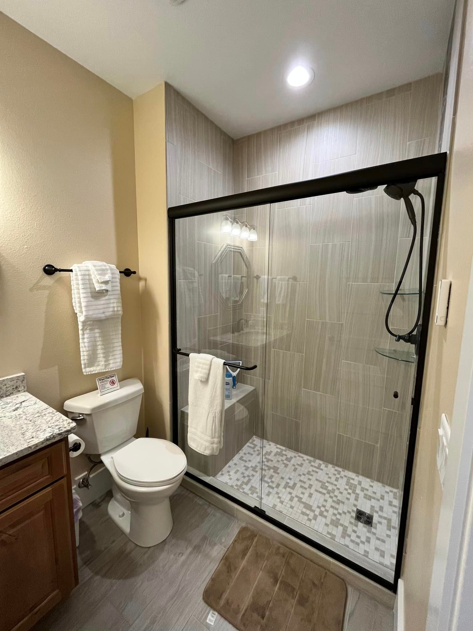 A bathroom with a toilet , sink , and walk in shower.