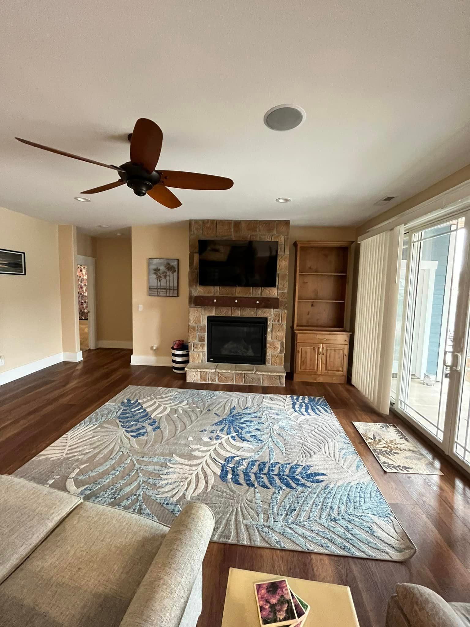 A living room with a fireplace and a ceiling fan.
