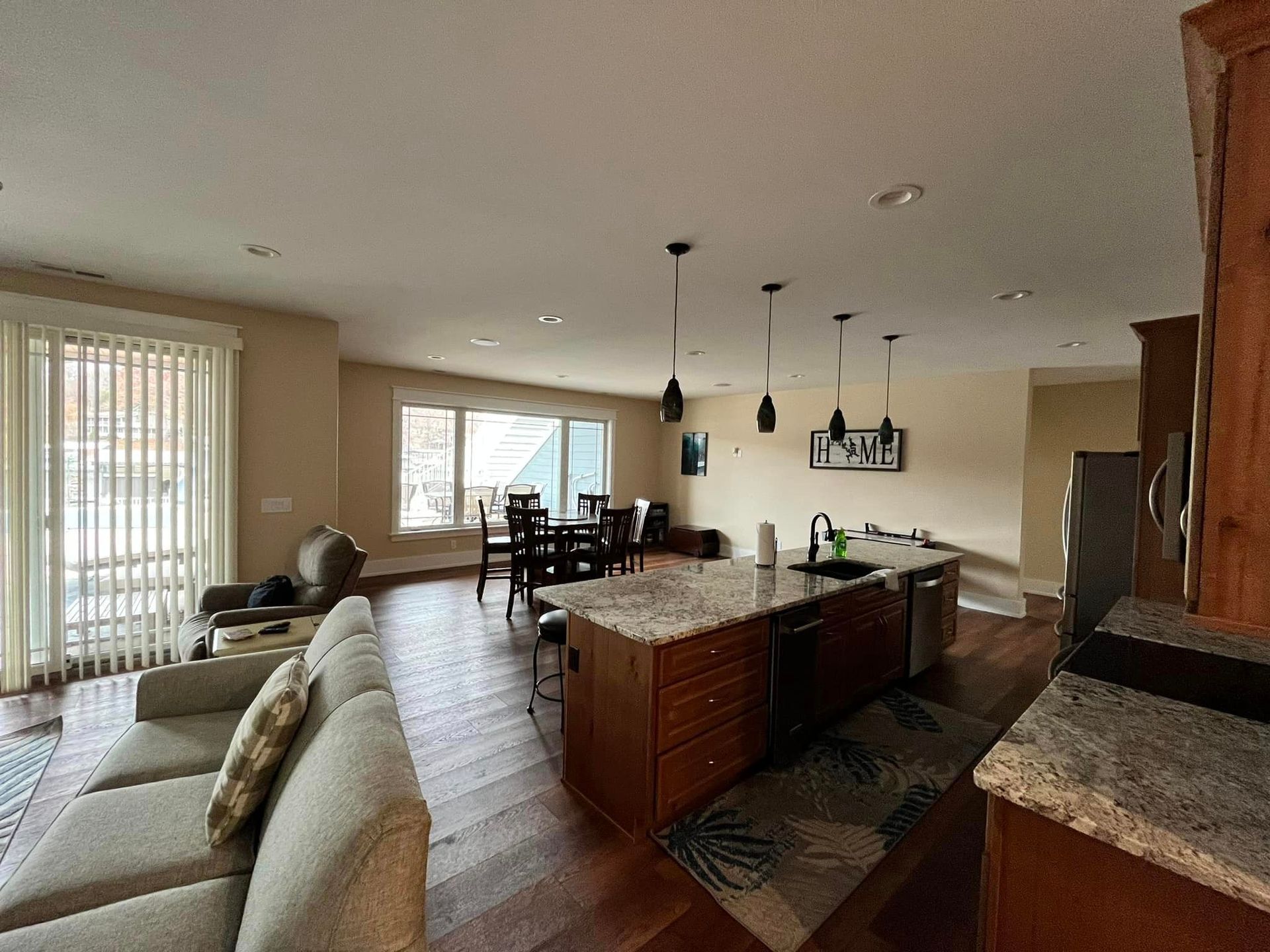 A living room with a couch , chairs , a table and a kitchen.