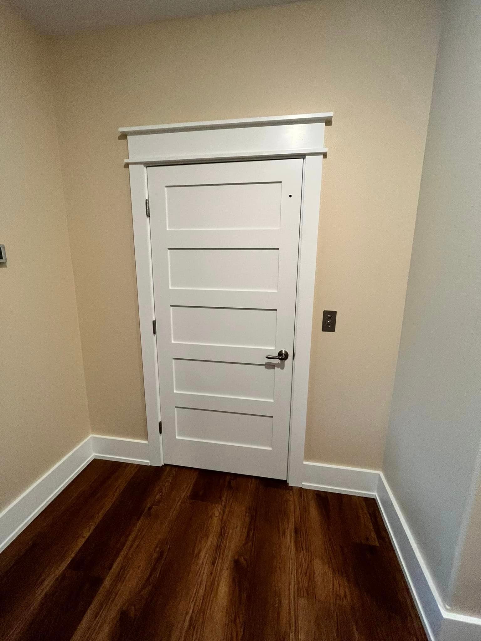 A white door with a wooden floor in a room.