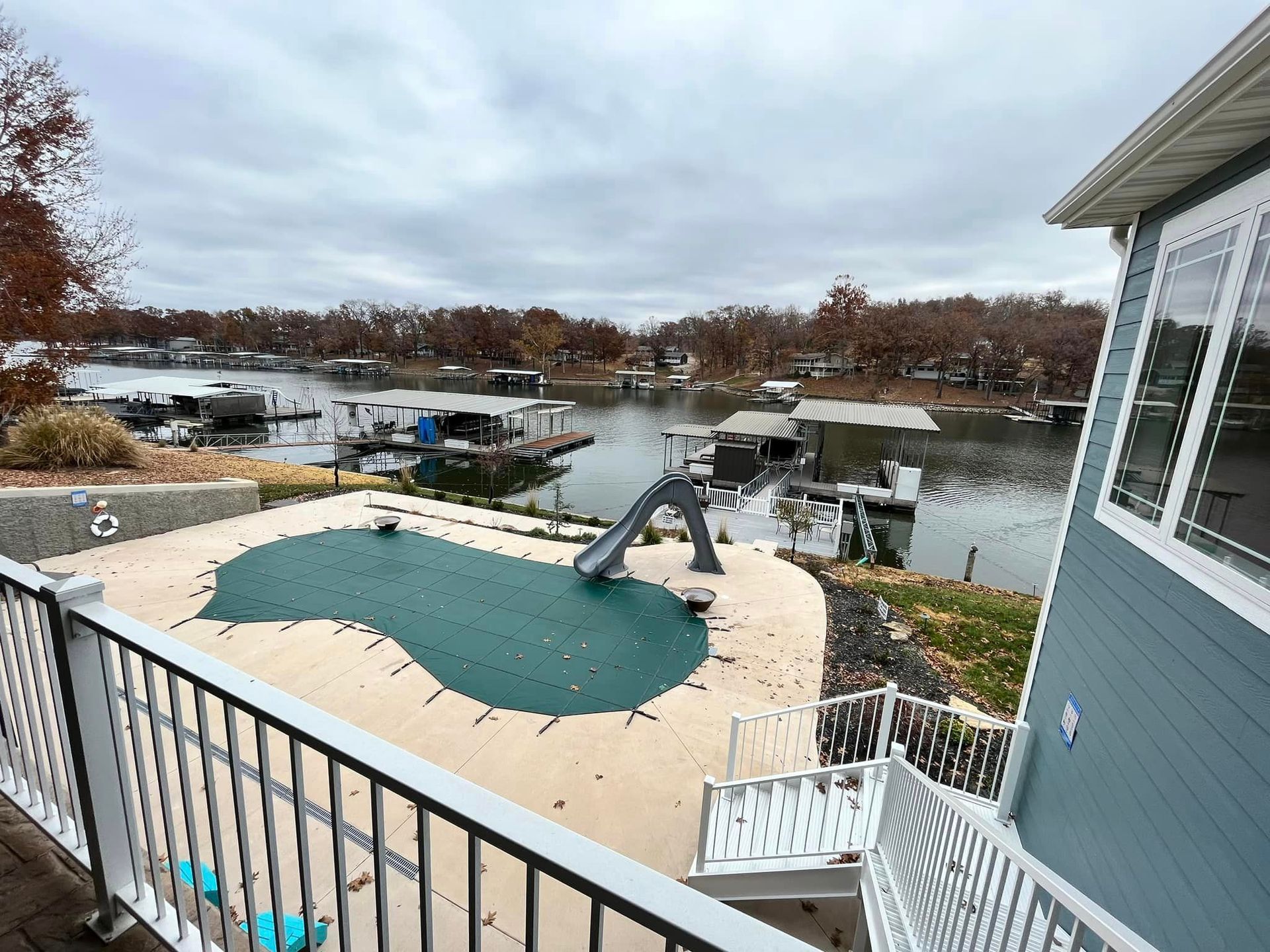 A view of a swimming pool from a balcony overlooking a lake.