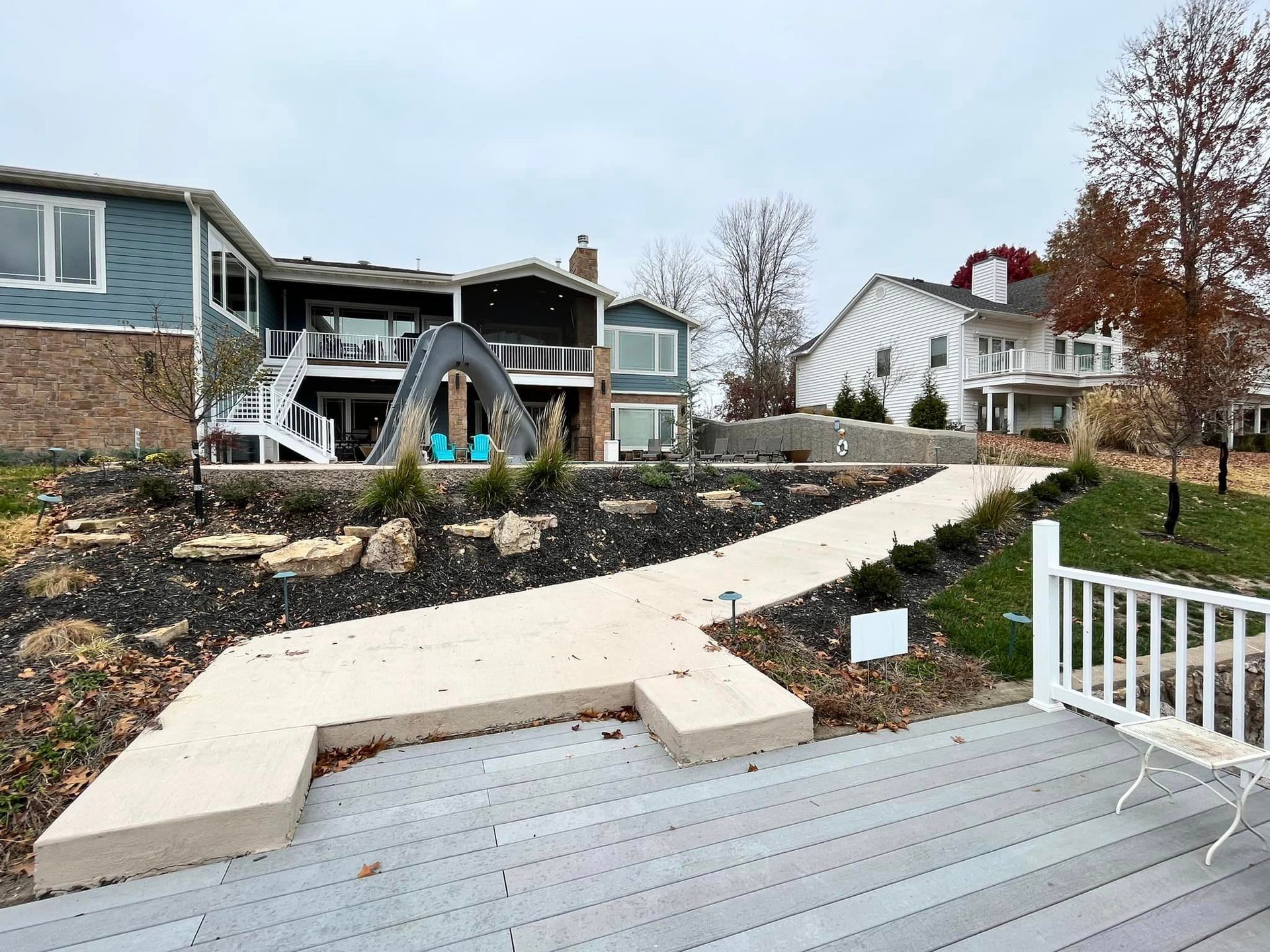 A house with a walkway leading to it and a deck in front of it.