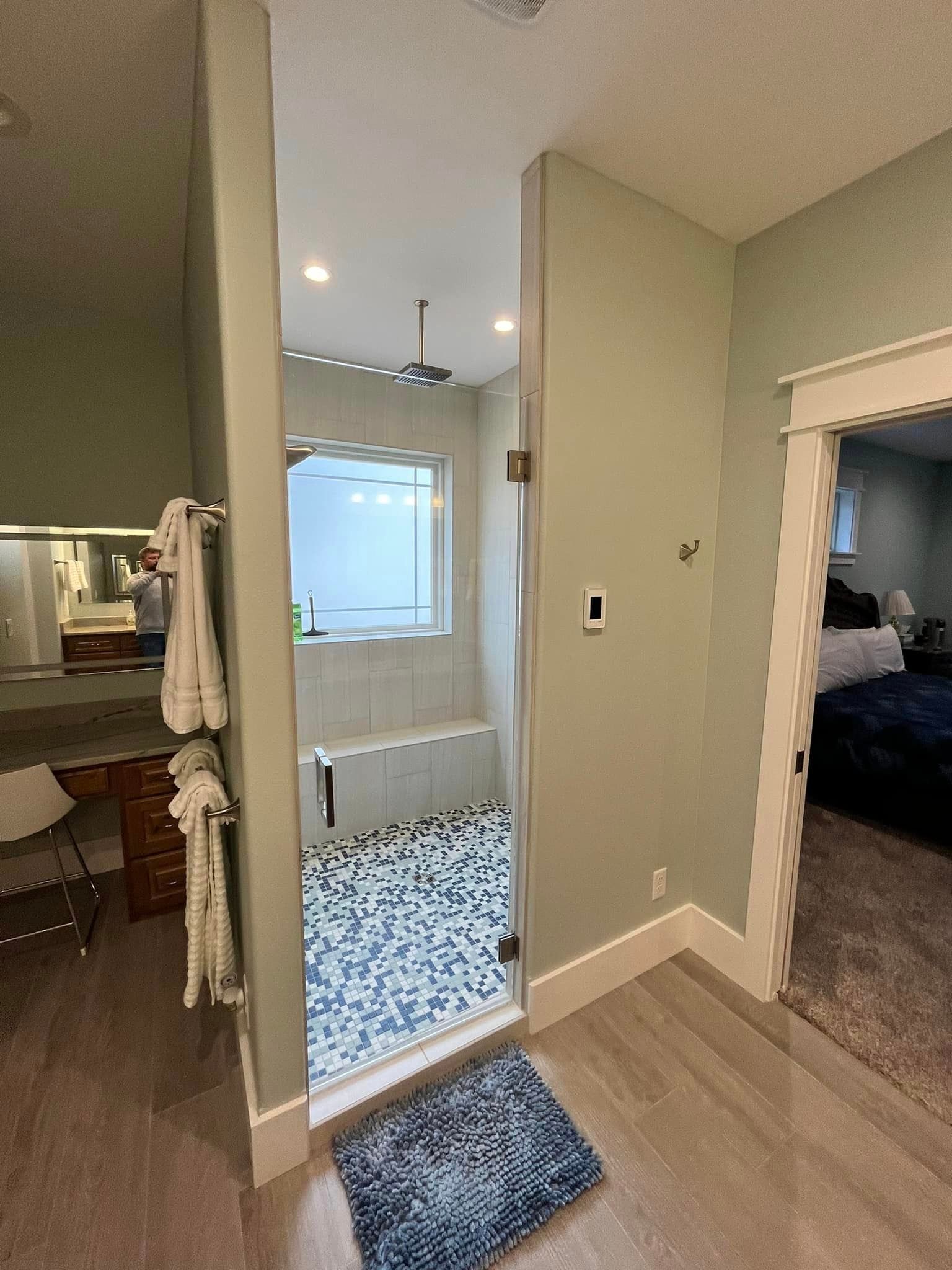 A bathroom with a walk in shower and a blue rug on the floor.