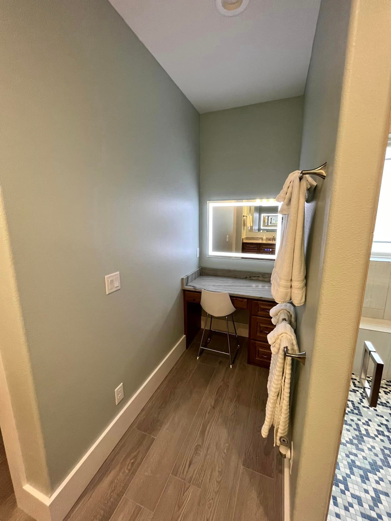A bathroom with a vanity , mirror and towels hanging on the wall.