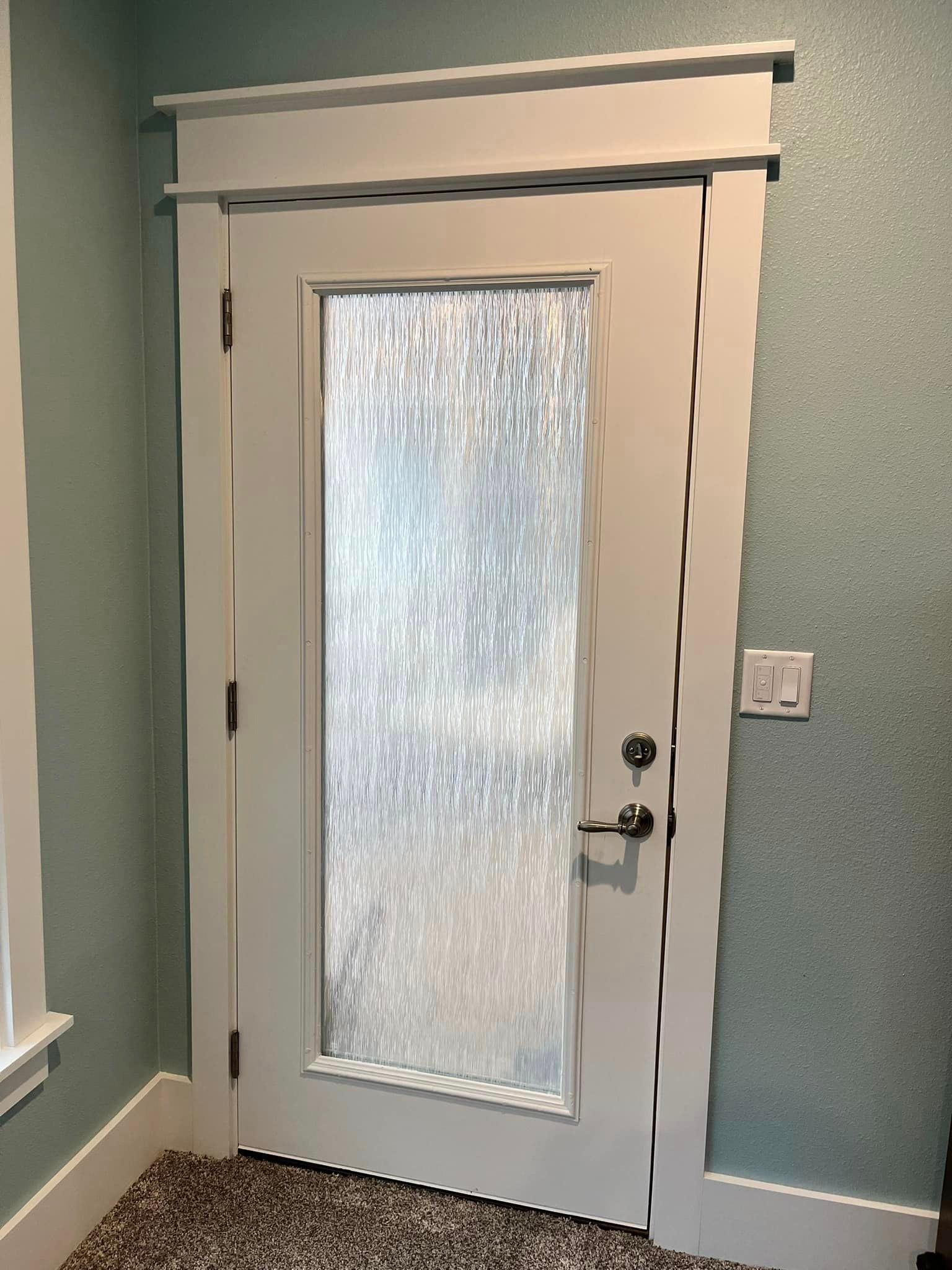 A white door with a clear glass window in a room