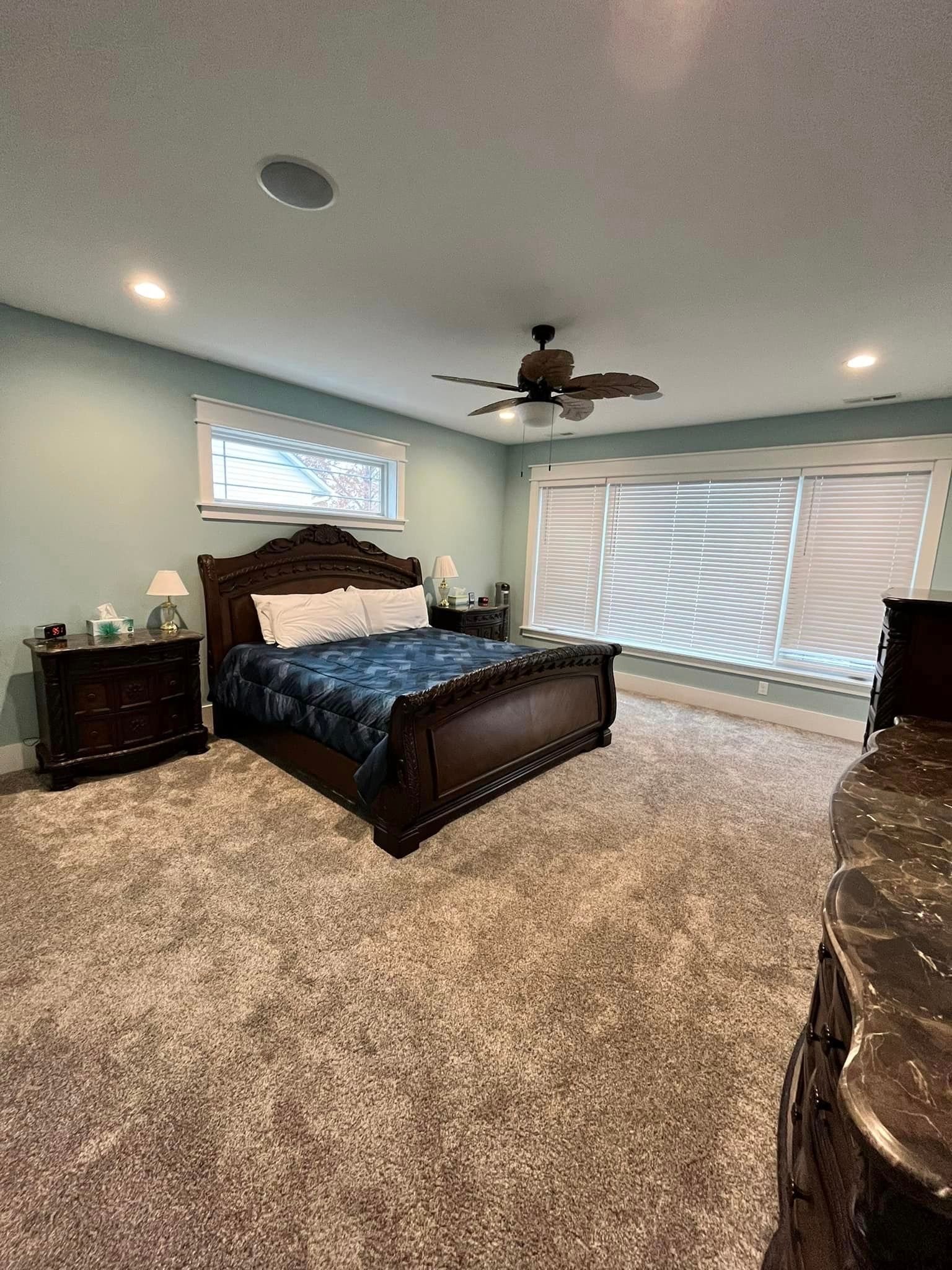 A bedroom with a bed , nightstand , dresser and ceiling fan.
