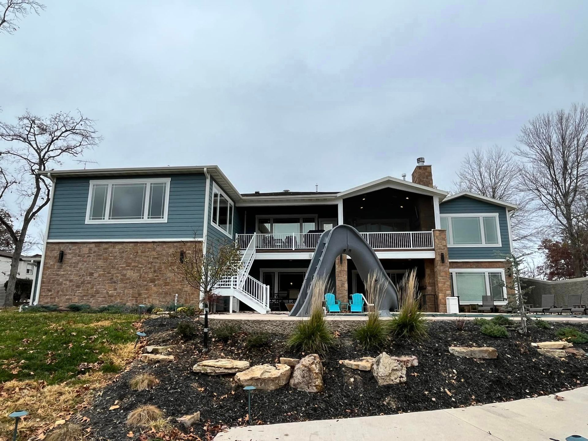 The back of a large house with a large deck and stairs.