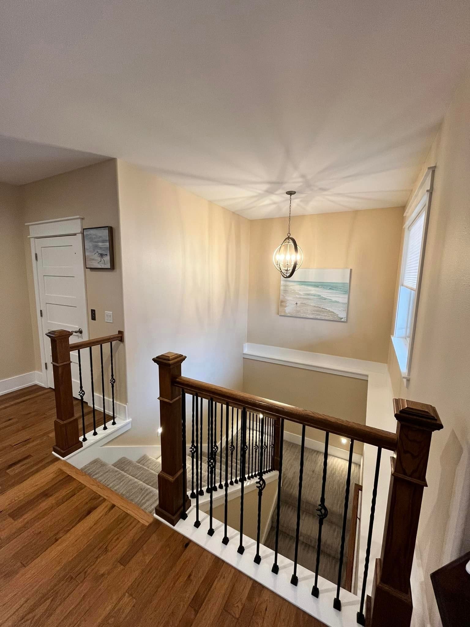A staircase in a house with a wooden railing and a painting on the wall.