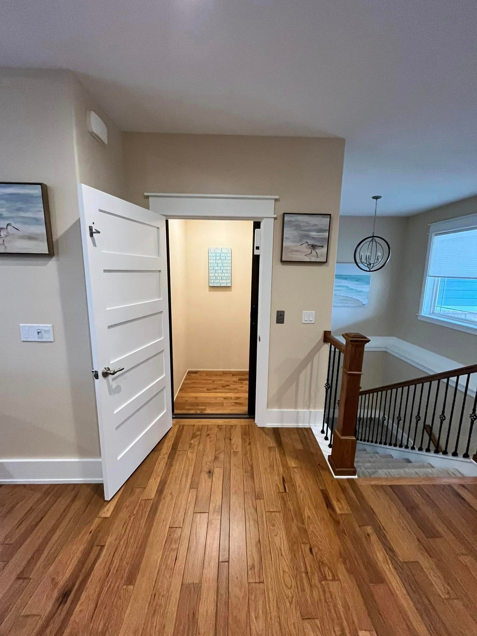 A hallway with hardwood floors and a staircase in a house.