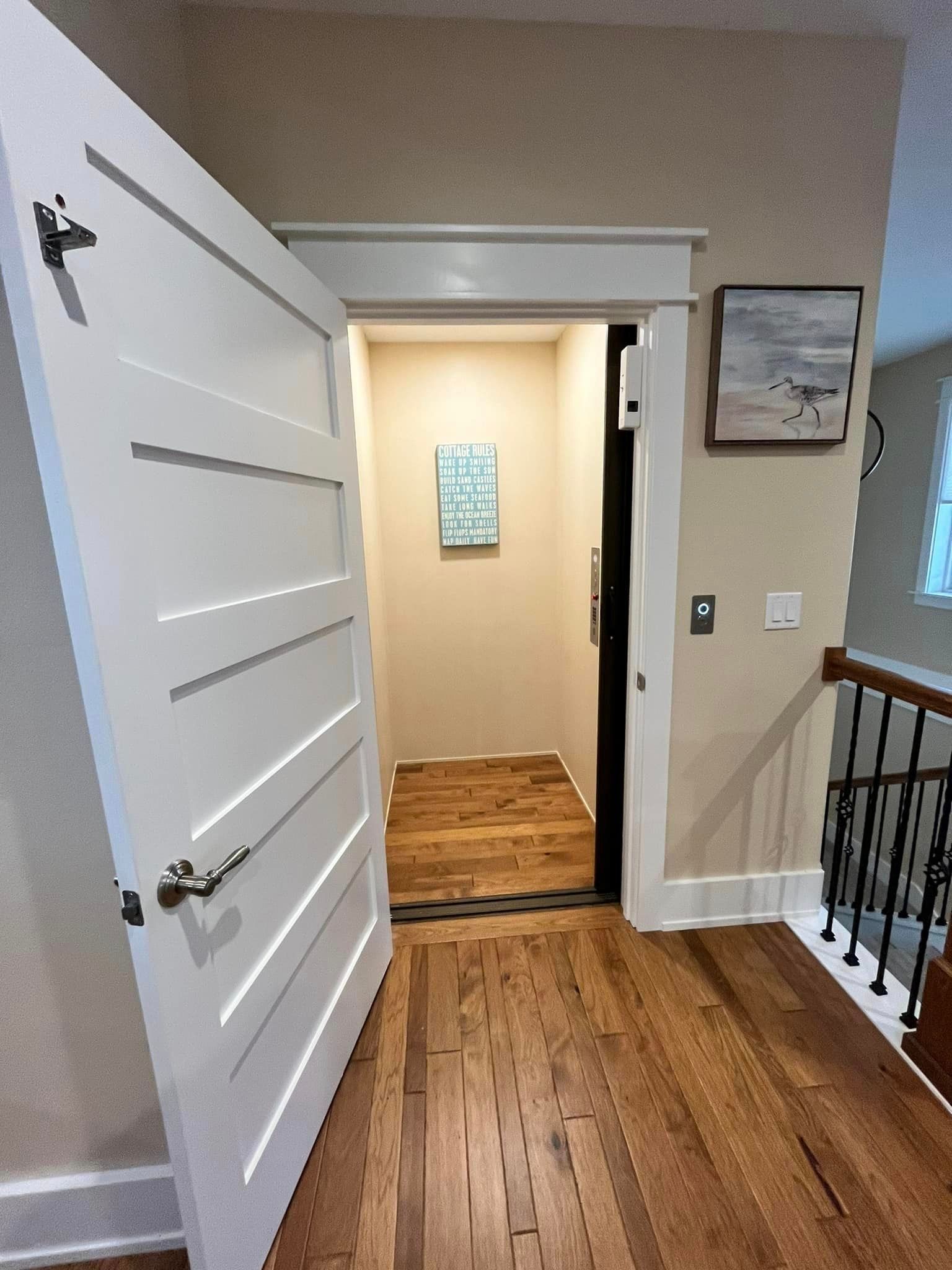 A hallway with a door open and a picture on the wall.