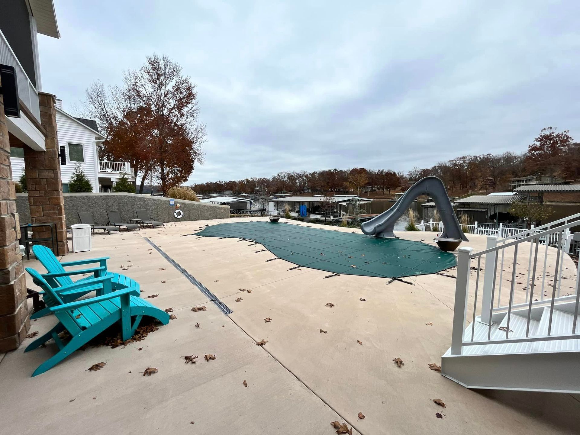 A patio with blue chairs and a slide in the background.