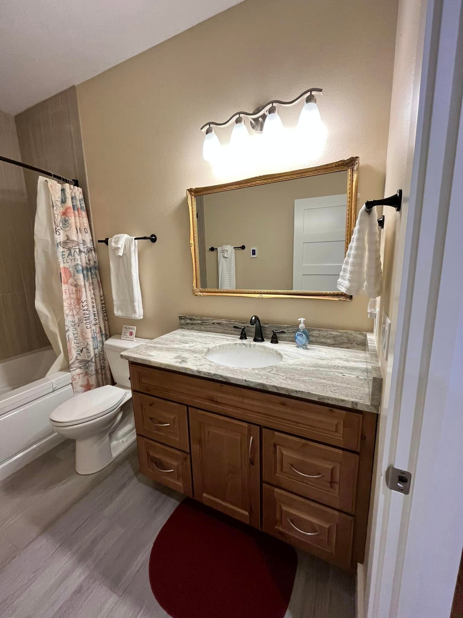 A bathroom with a sink , toilet , bathtub and mirror.