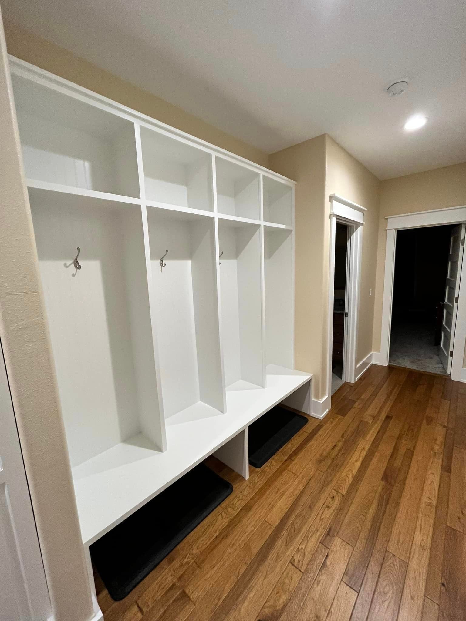 A hallway with hardwood floors and white shelves.
