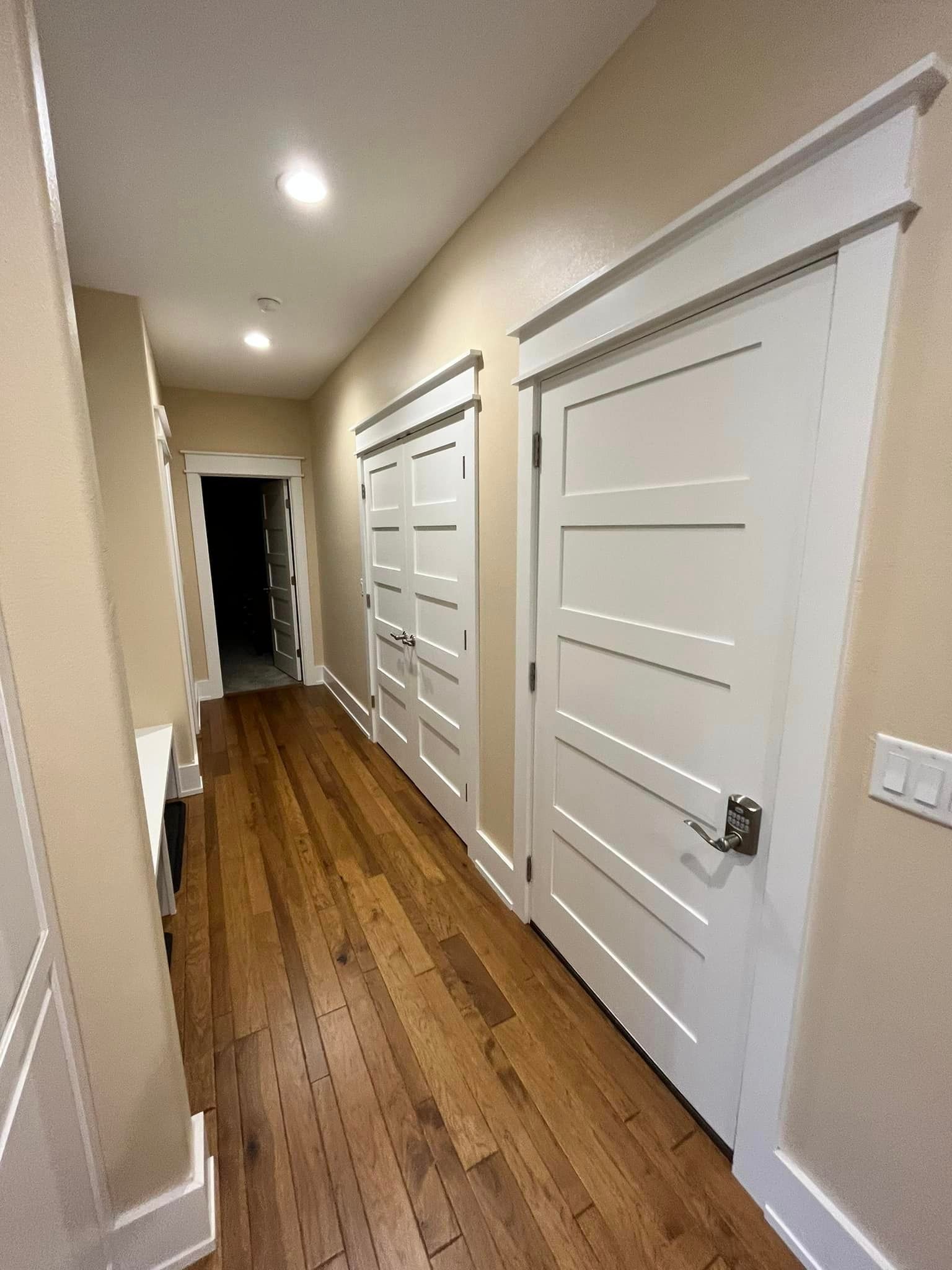 A long hallway with hardwood floors and white doors.