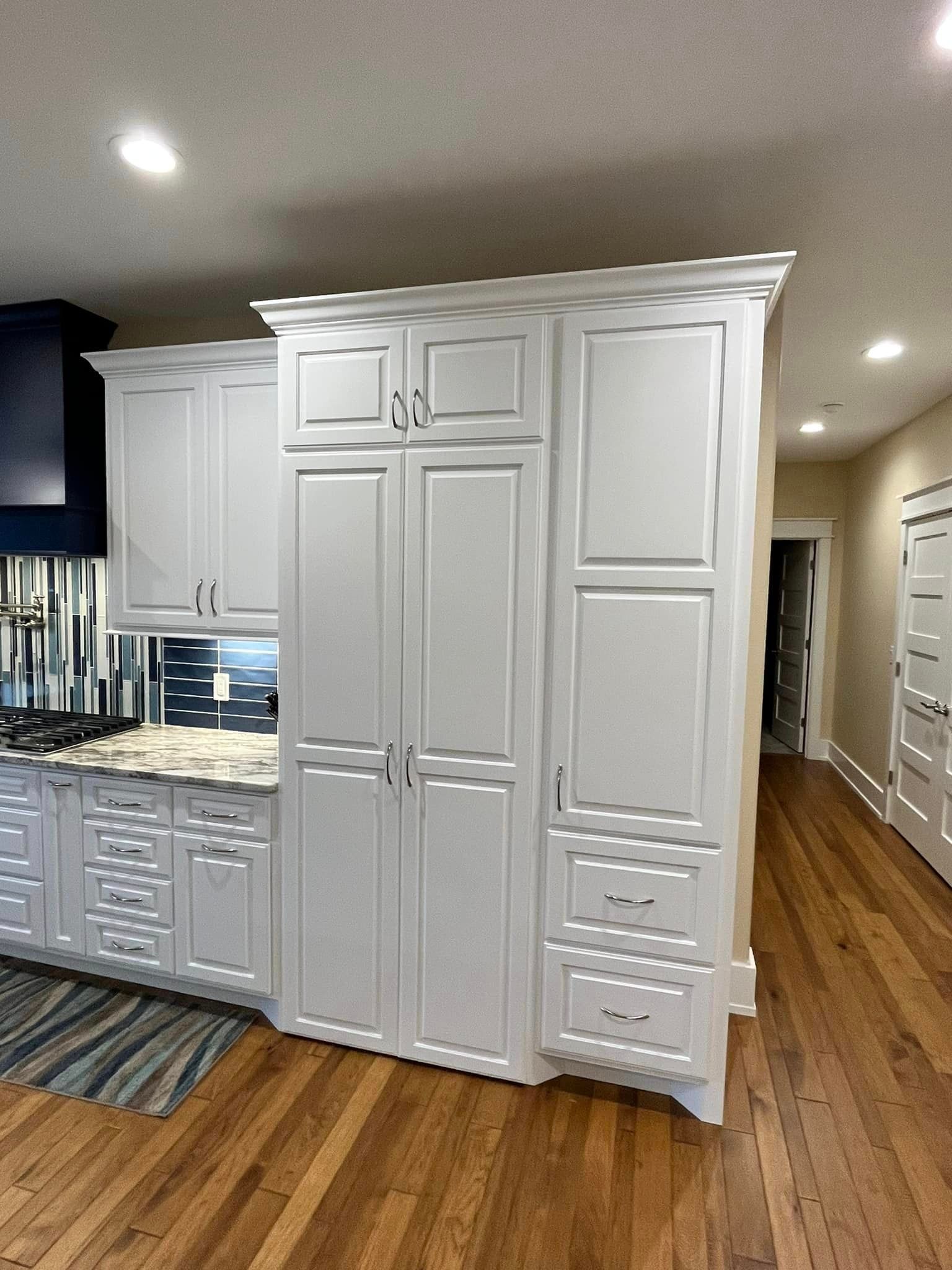 A kitchen with white cabinets and hardwood floors
