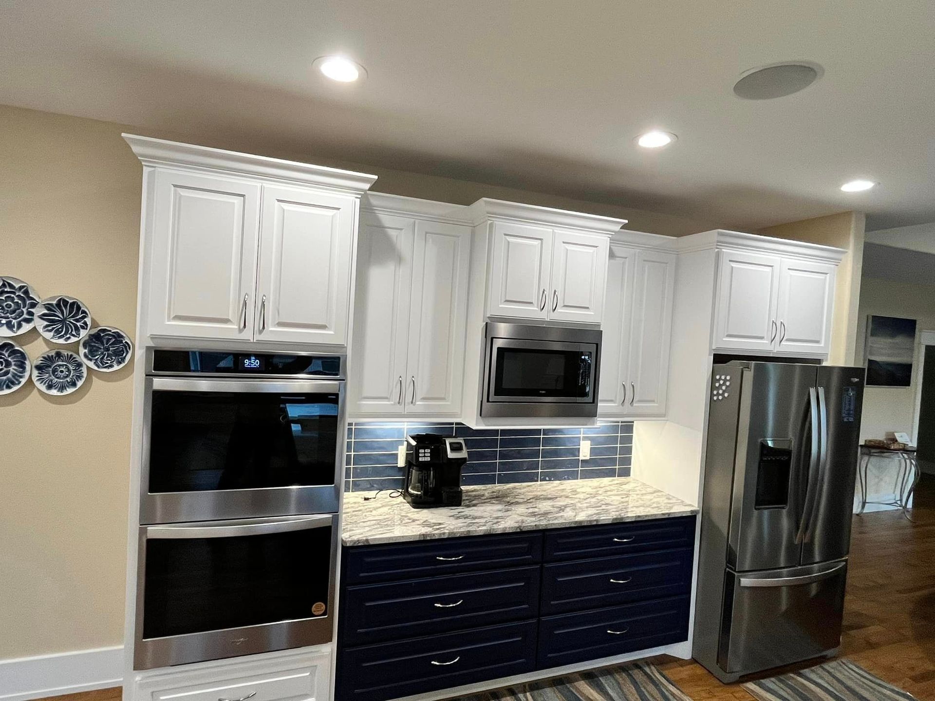 A kitchen with white cabinets , stainless steel appliances , a refrigerator and a microwave.