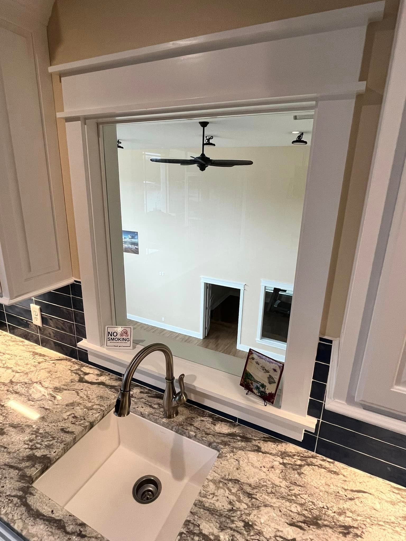A kitchen sink with a view of a living room through a window.