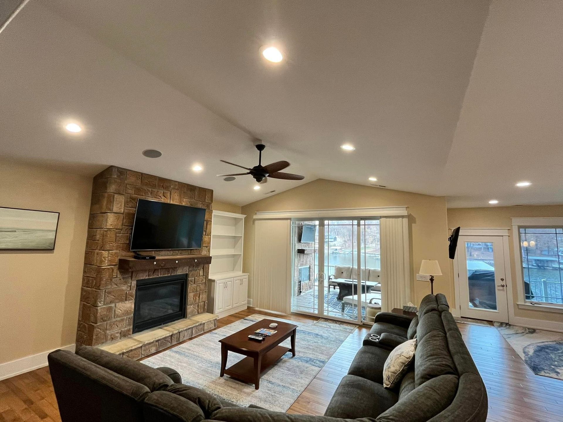 A living room with a couch , fireplace , television and ceiling fan.
