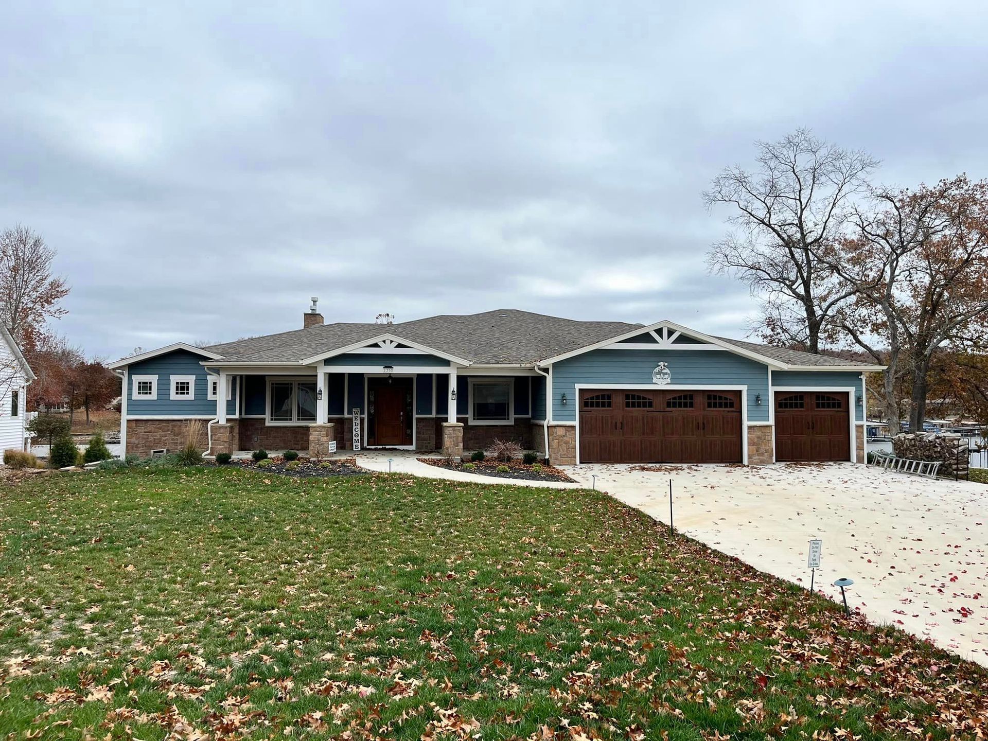 A large house with two garages and a large lawn in front of it.