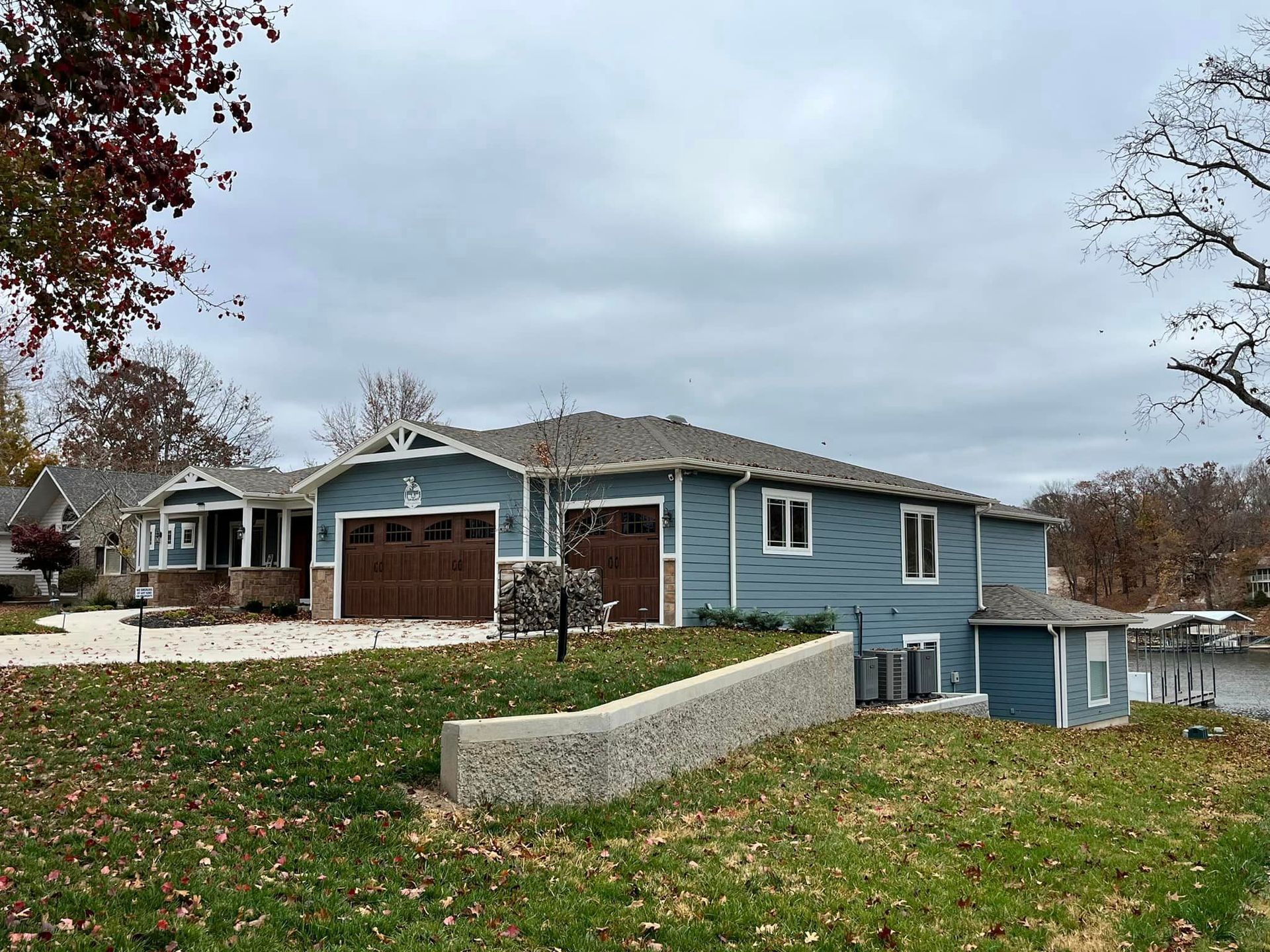 A blue house with a brown garage door is sitting on top of a grassy hill.