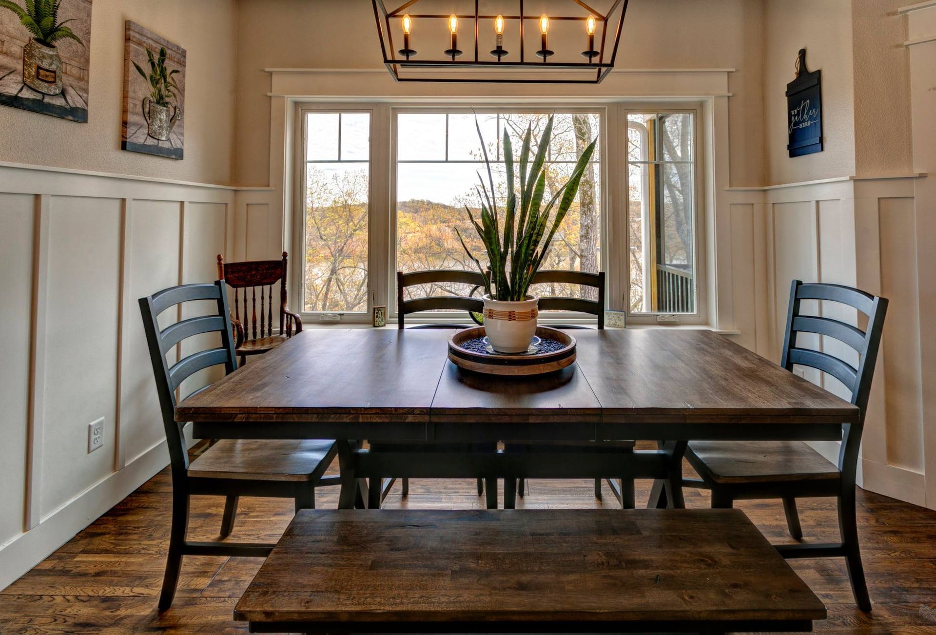 A dining room with a table and chairs and a plant on the table.