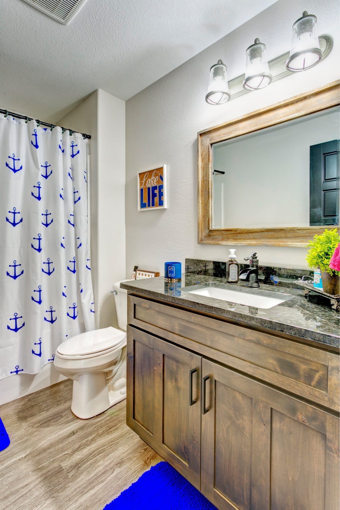 A bathroom with a toilet , sink , mirror and shower curtain.