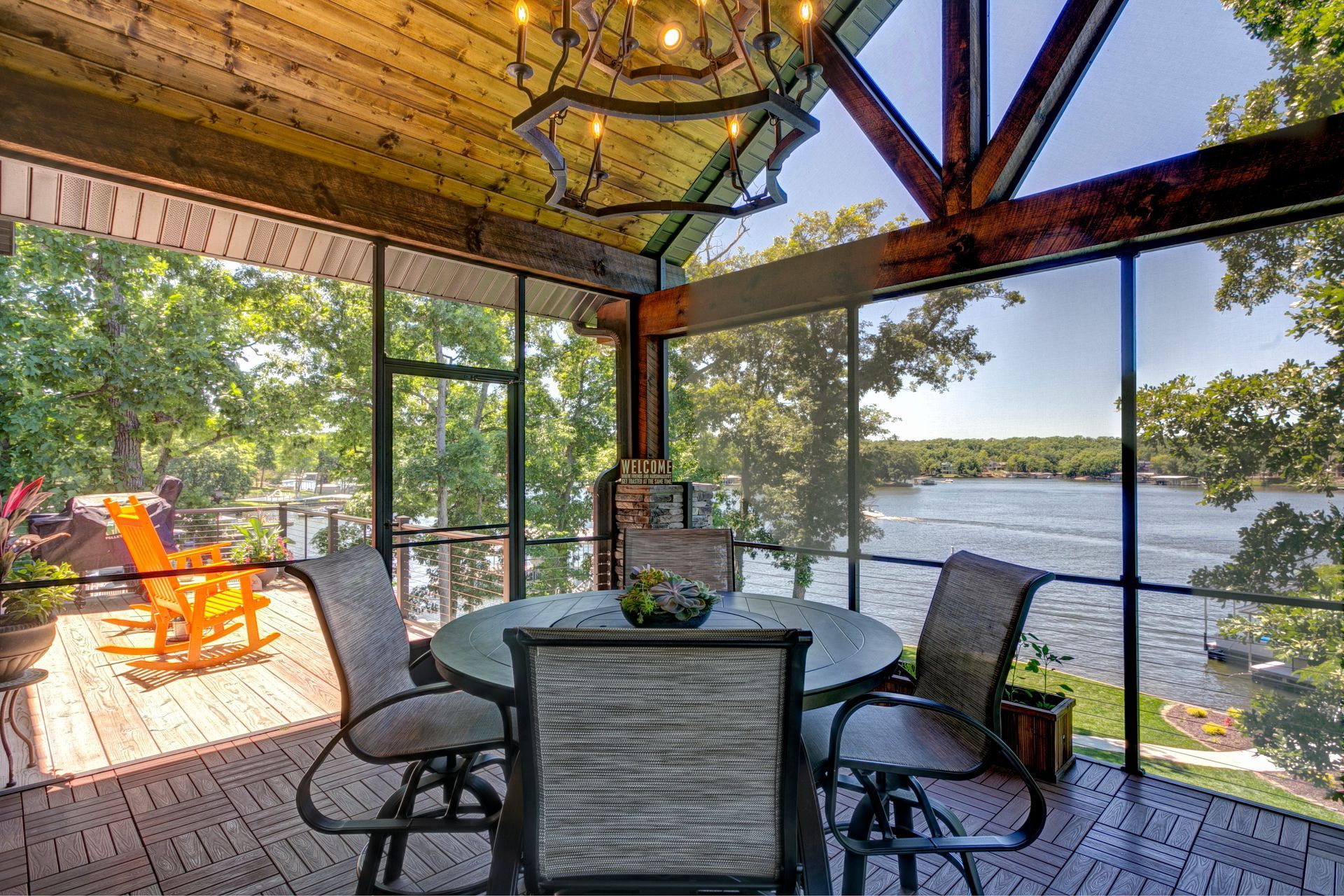 A screened in porch with a table and chairs overlooking a lake.