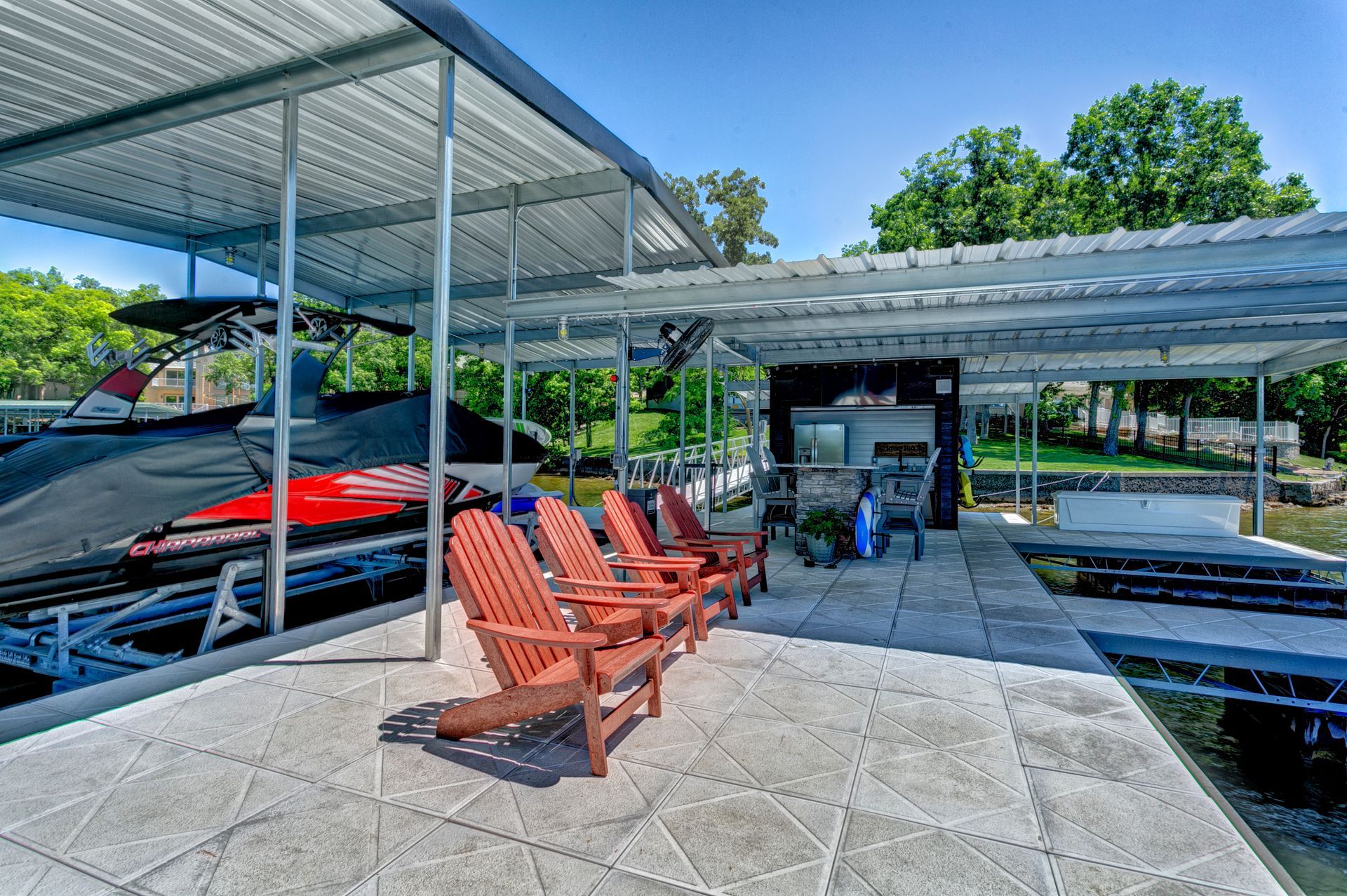 A dock with chairs and a jet ski in the background.