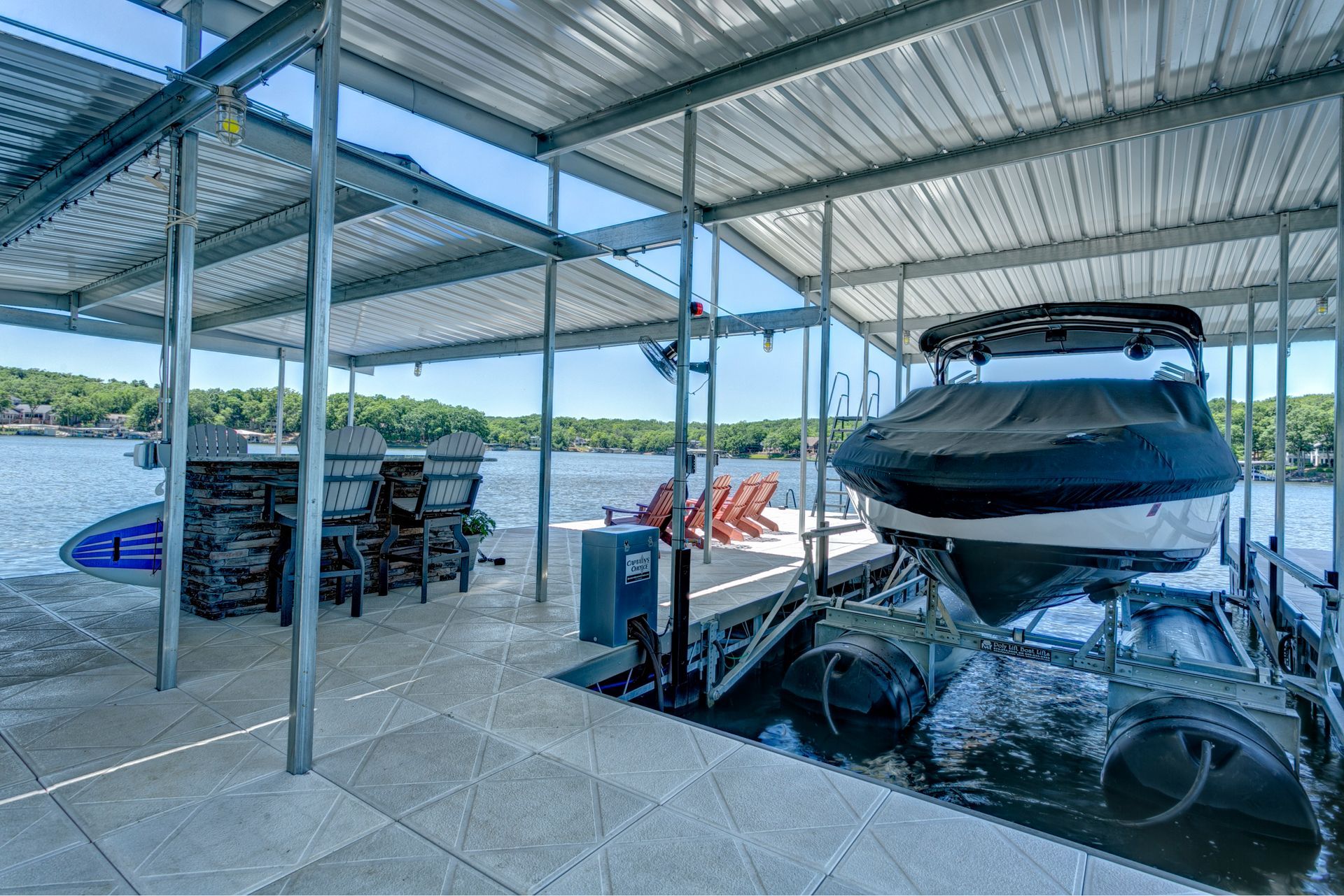 A boat is docked in a covered dock on a lake.