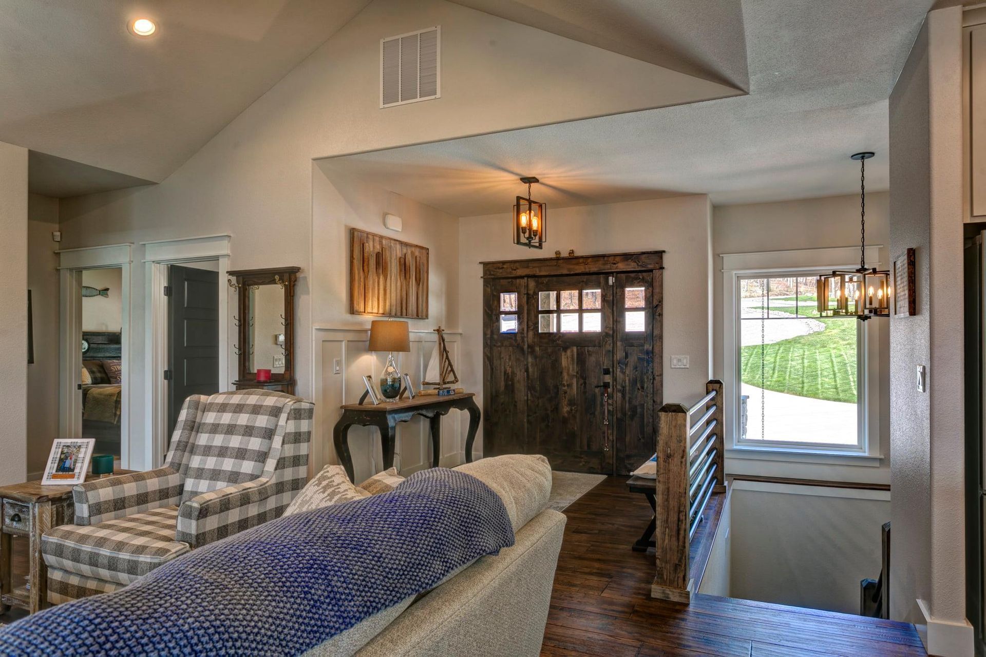 A living room with a couch , chairs , and a wooden door.