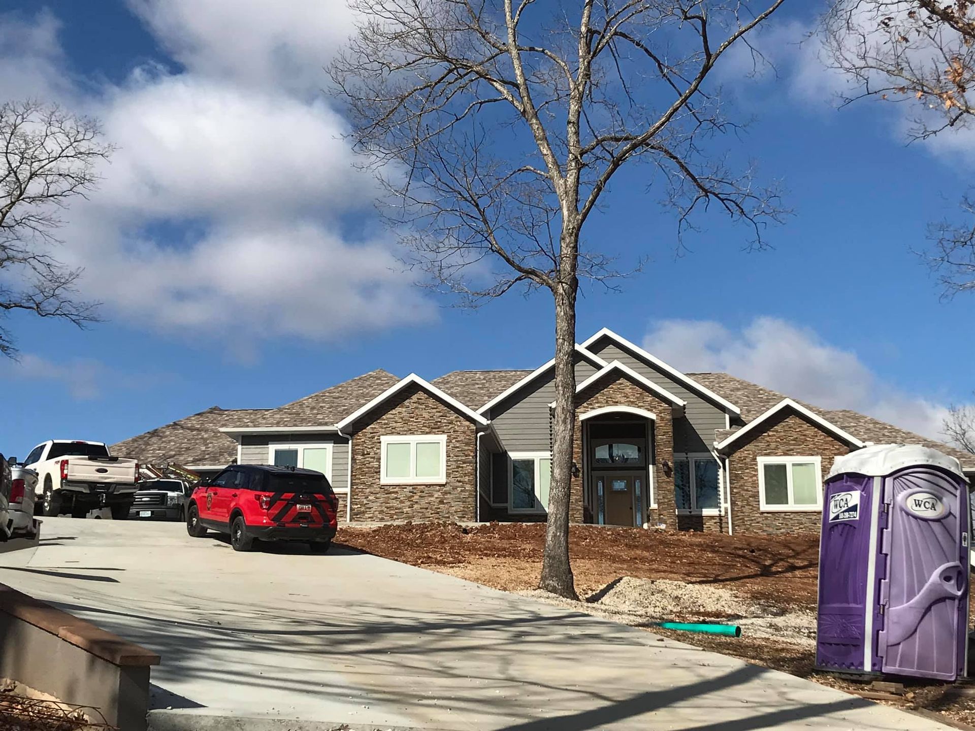 A large house with a purple portable toilet in front of it.