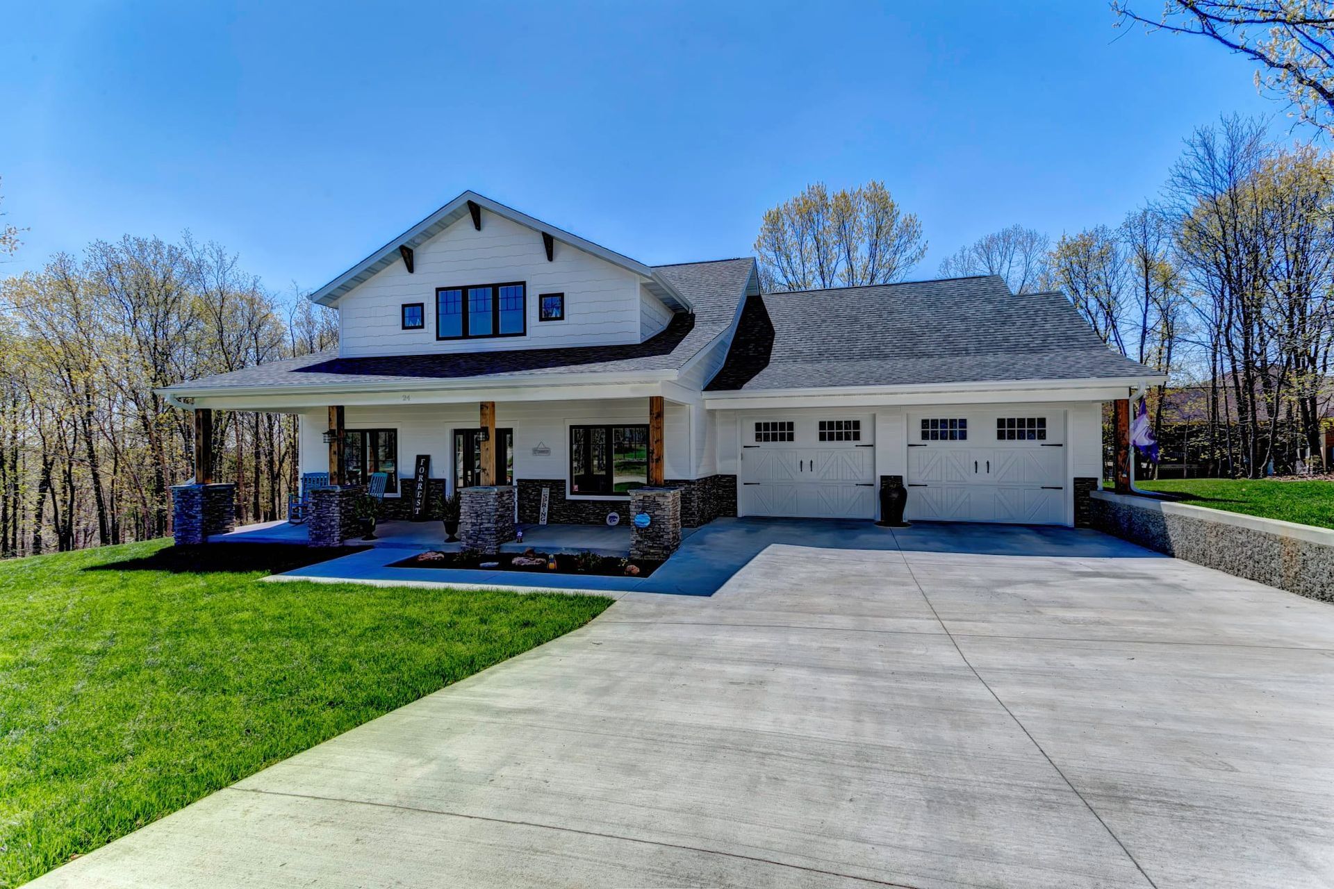 A large white house with a concrete driveway in front of it.