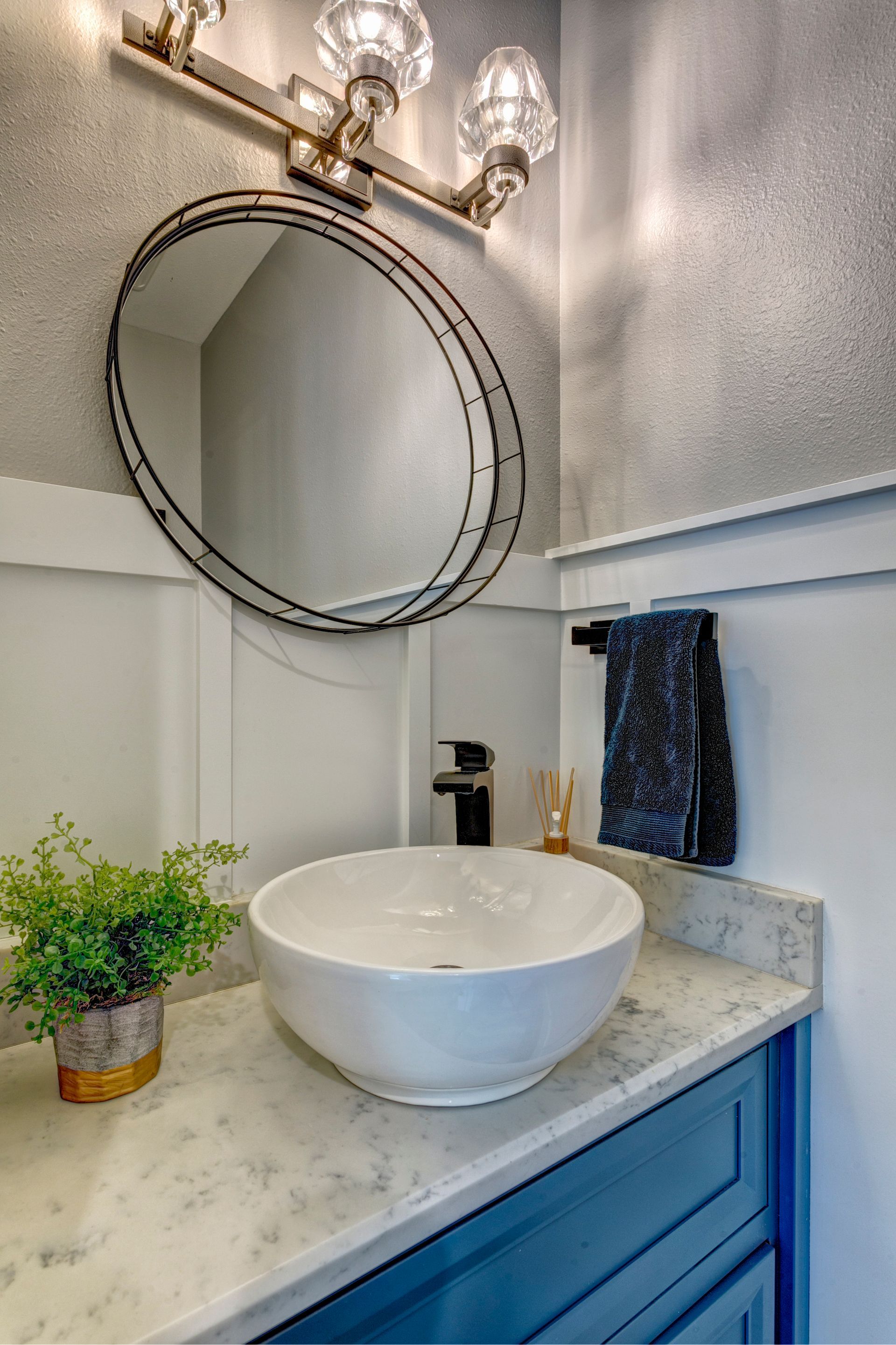 A bathroom with a sink , mirror , and blue cabinets.