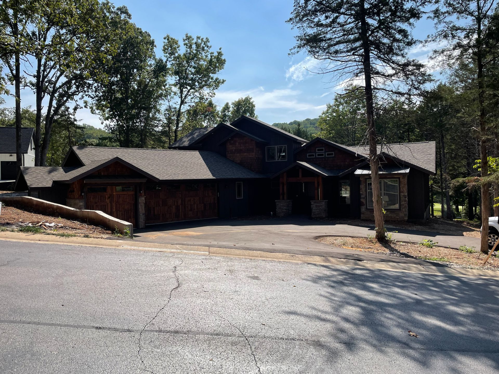 A large house is sitting on the side of a road surrounded by trees.