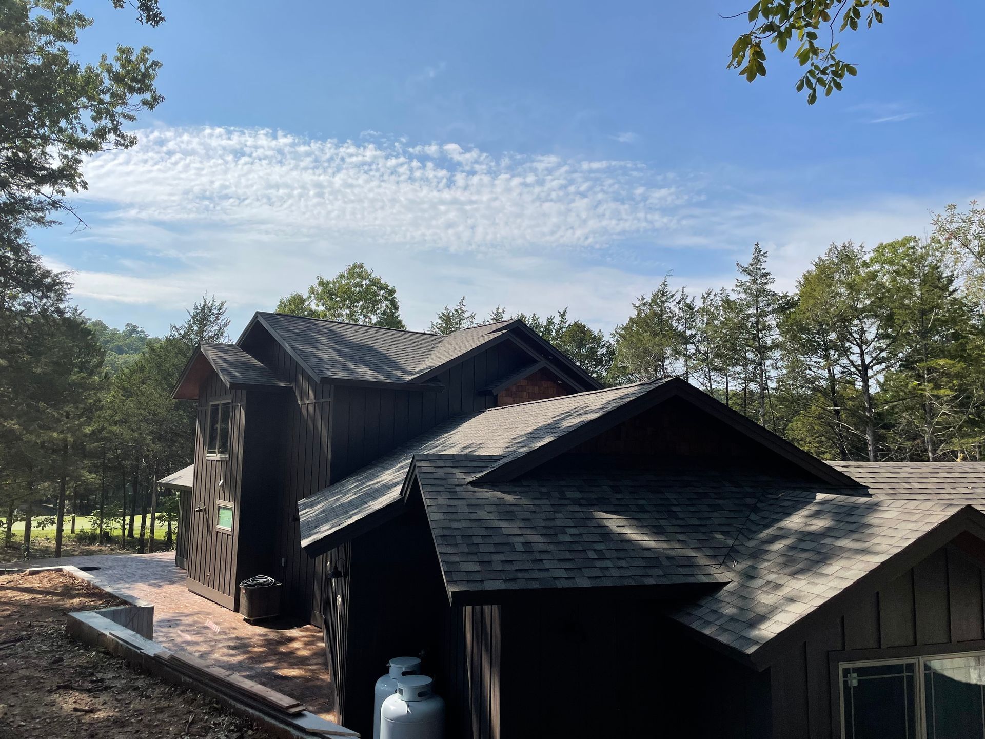 A large house with a lot of windows is surrounded by trees on a sunny day.