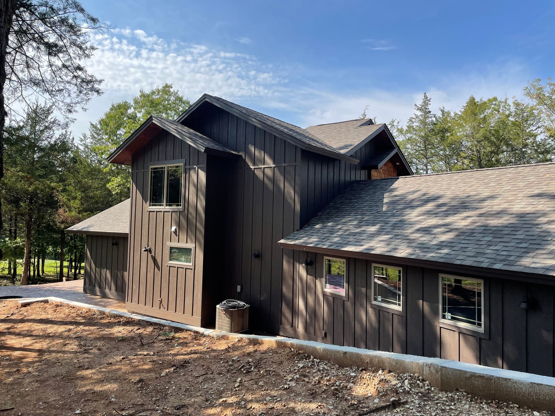 A large house with a lot of windows is sitting on top of a dirt hill.