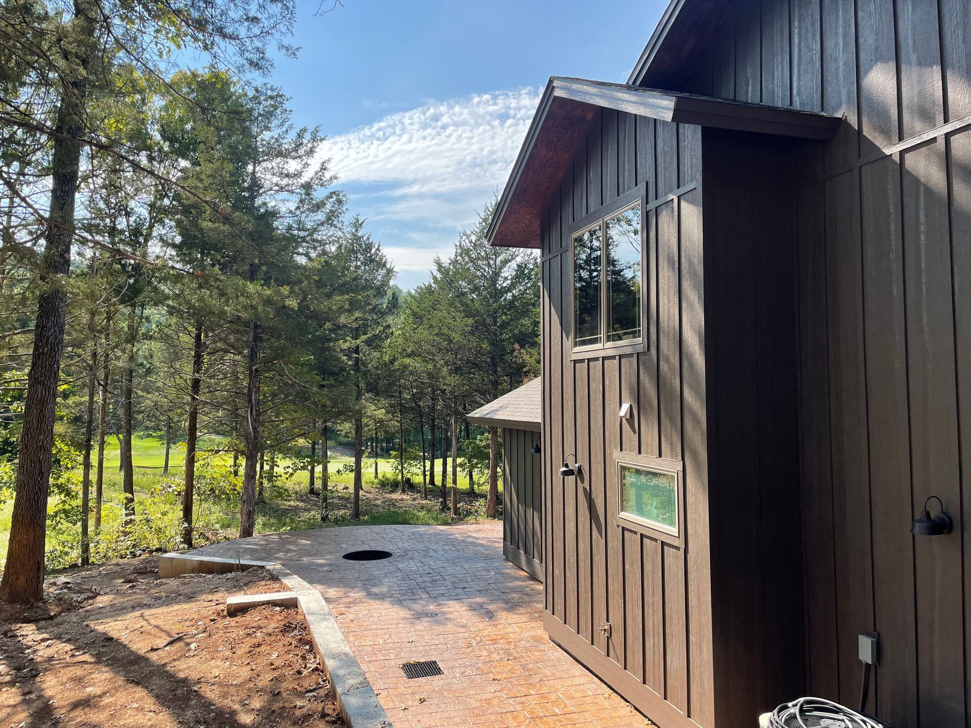 A brown house with a lot of windows is surrounded by trees.